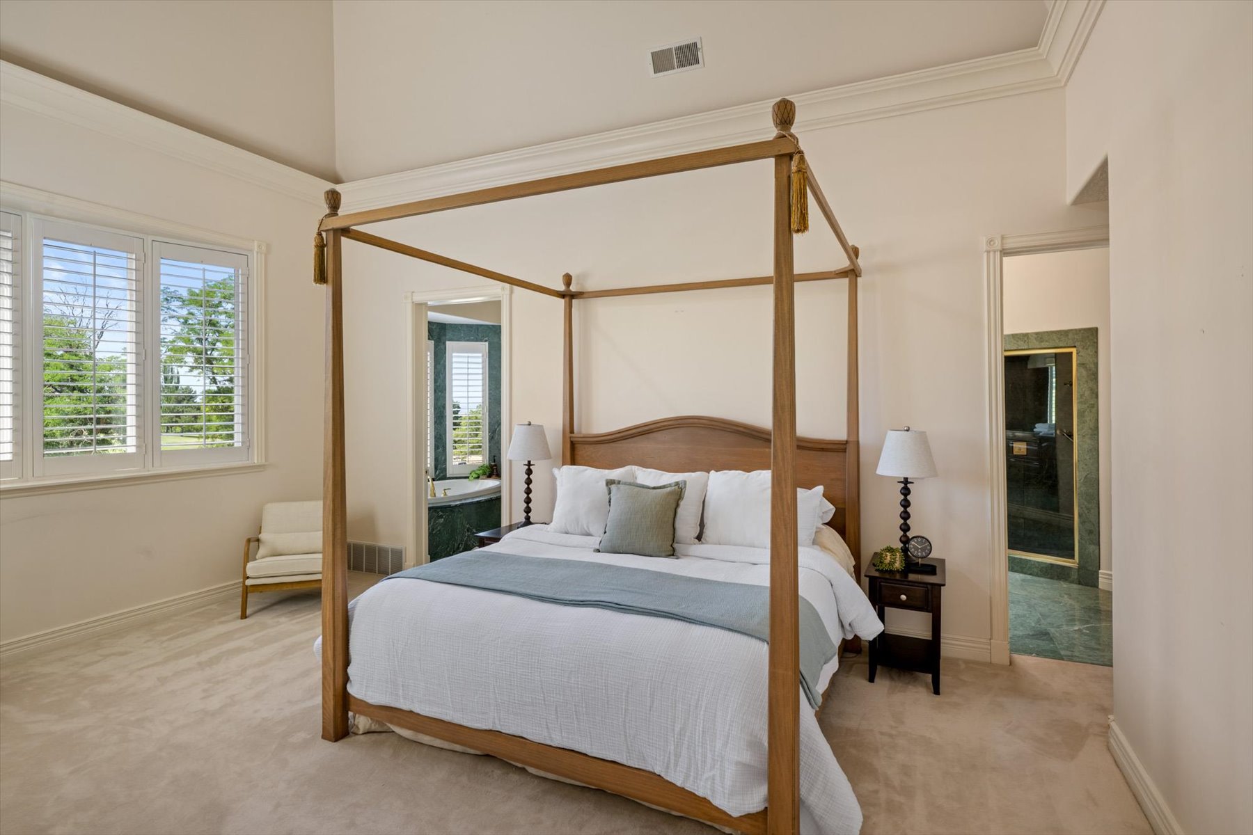 Carpeted bedroom featuring an arched doorway, vaulted ceiling, and crown molding