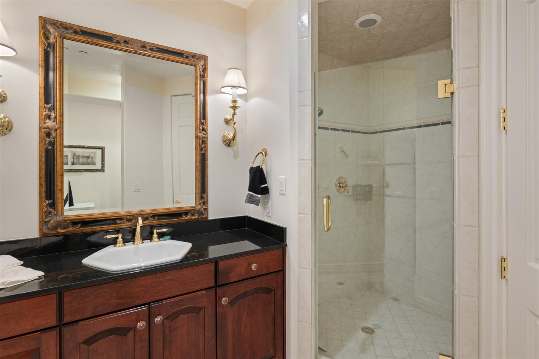 Bathroom featuring a dark wood-finish vanity with an octagonal vessel sink, gold-tone hardware, and a black countertop