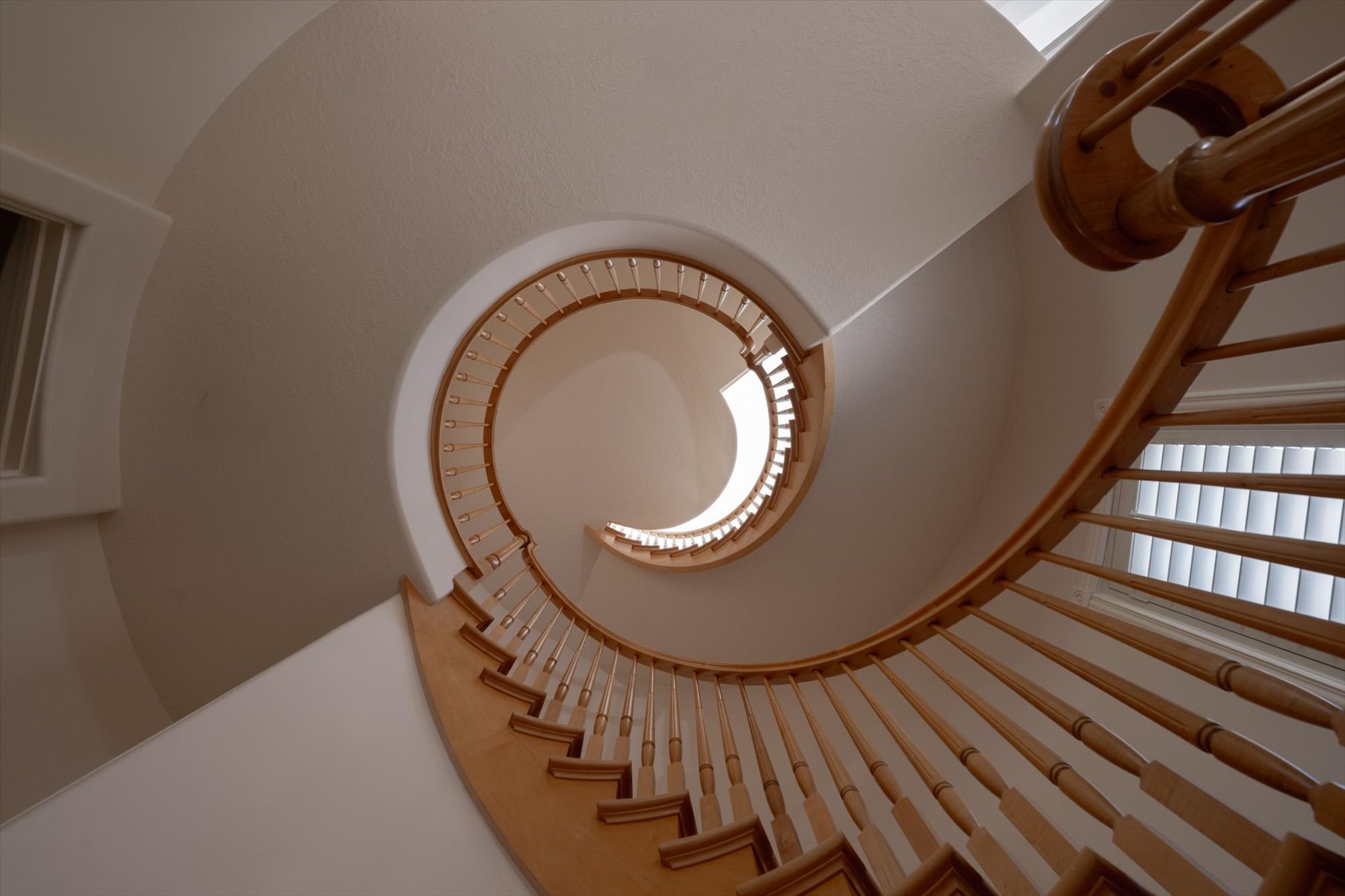 Spiral staircase featuring natural wood handrail and balusters