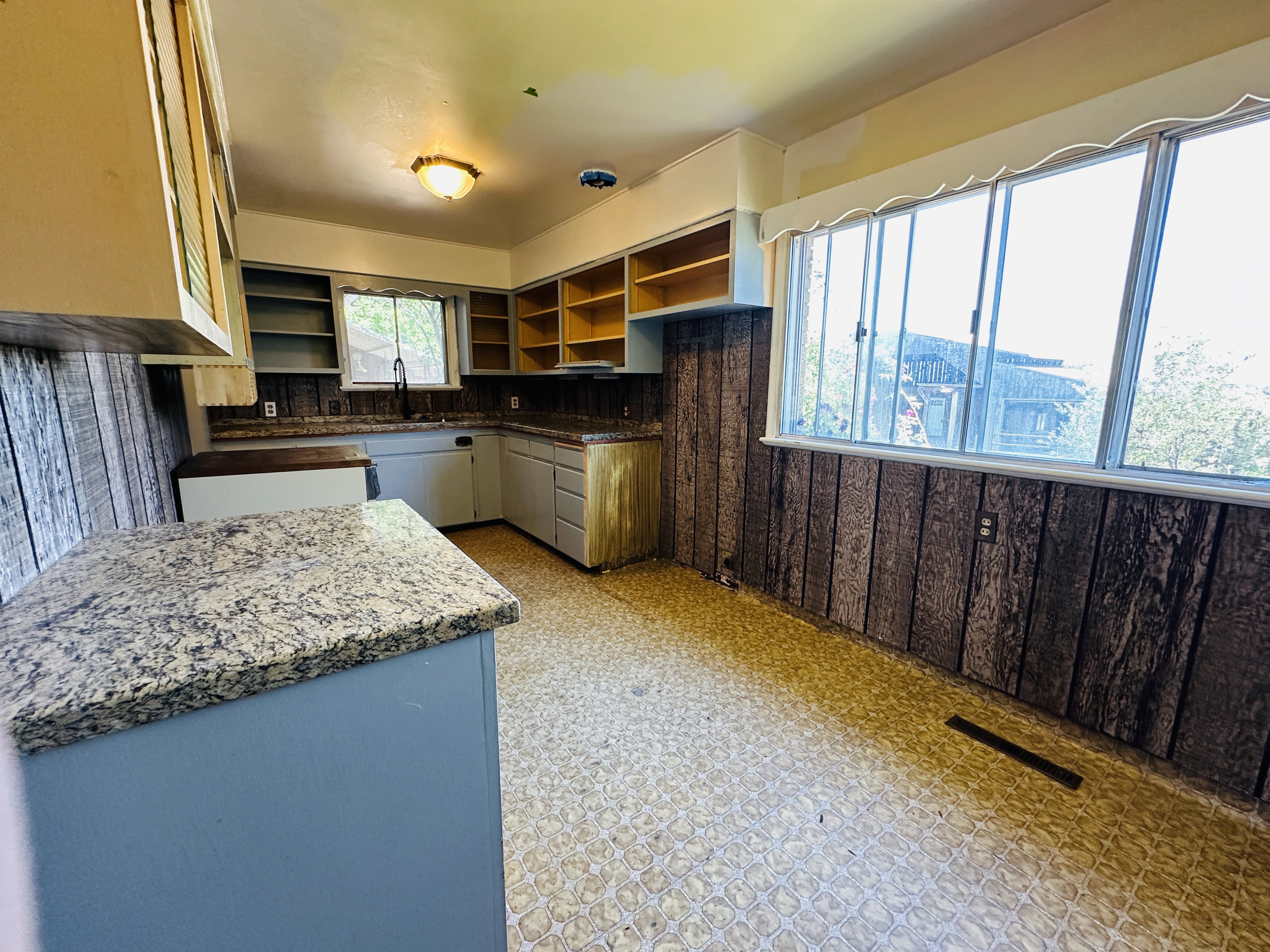 Kitchen featuring a corner sink, open shelving, and a patterned floor