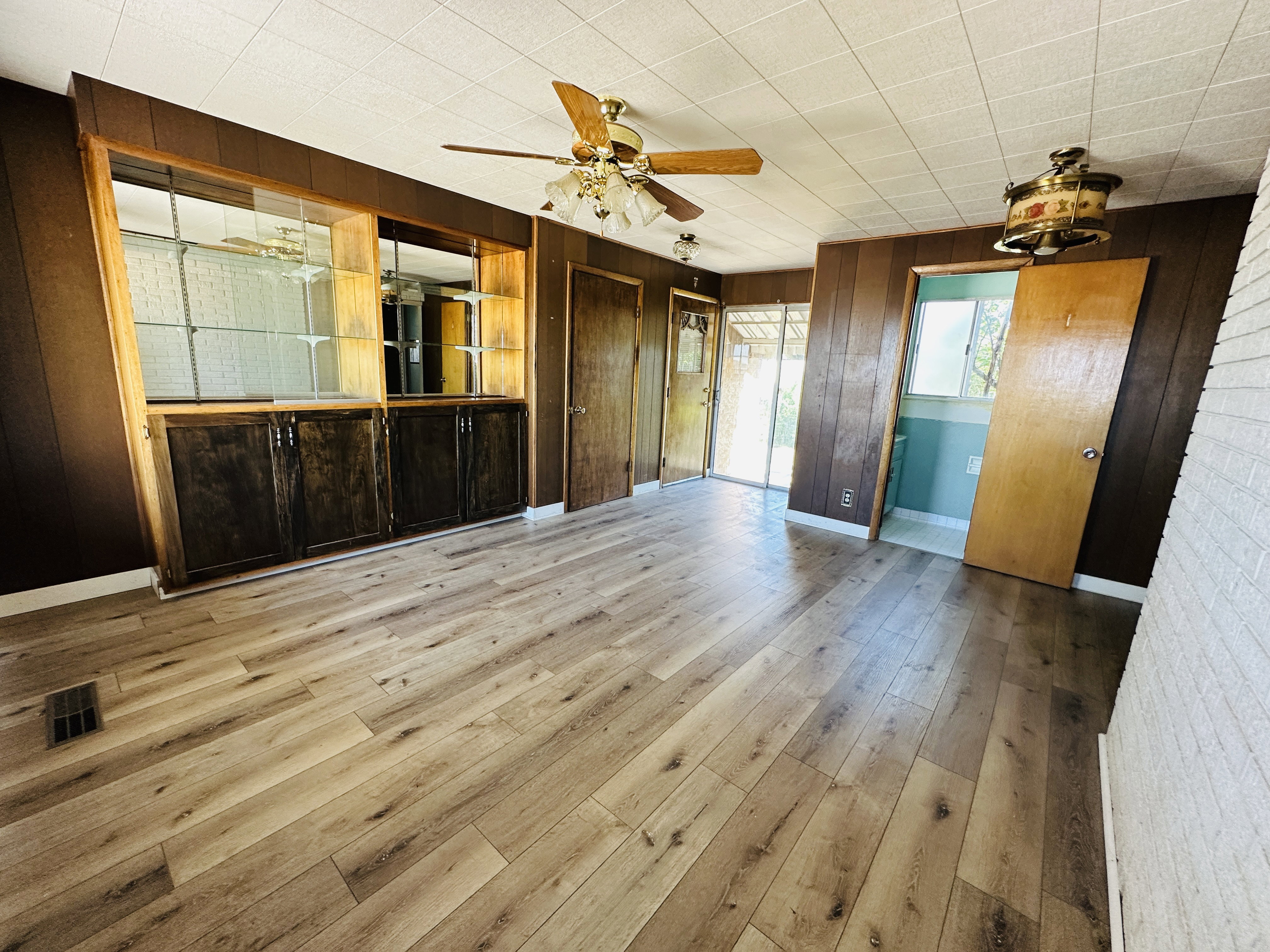 Expansive room featuring wood-finish flooring, a built-in display cabinet with glass shelving, and wood paneling