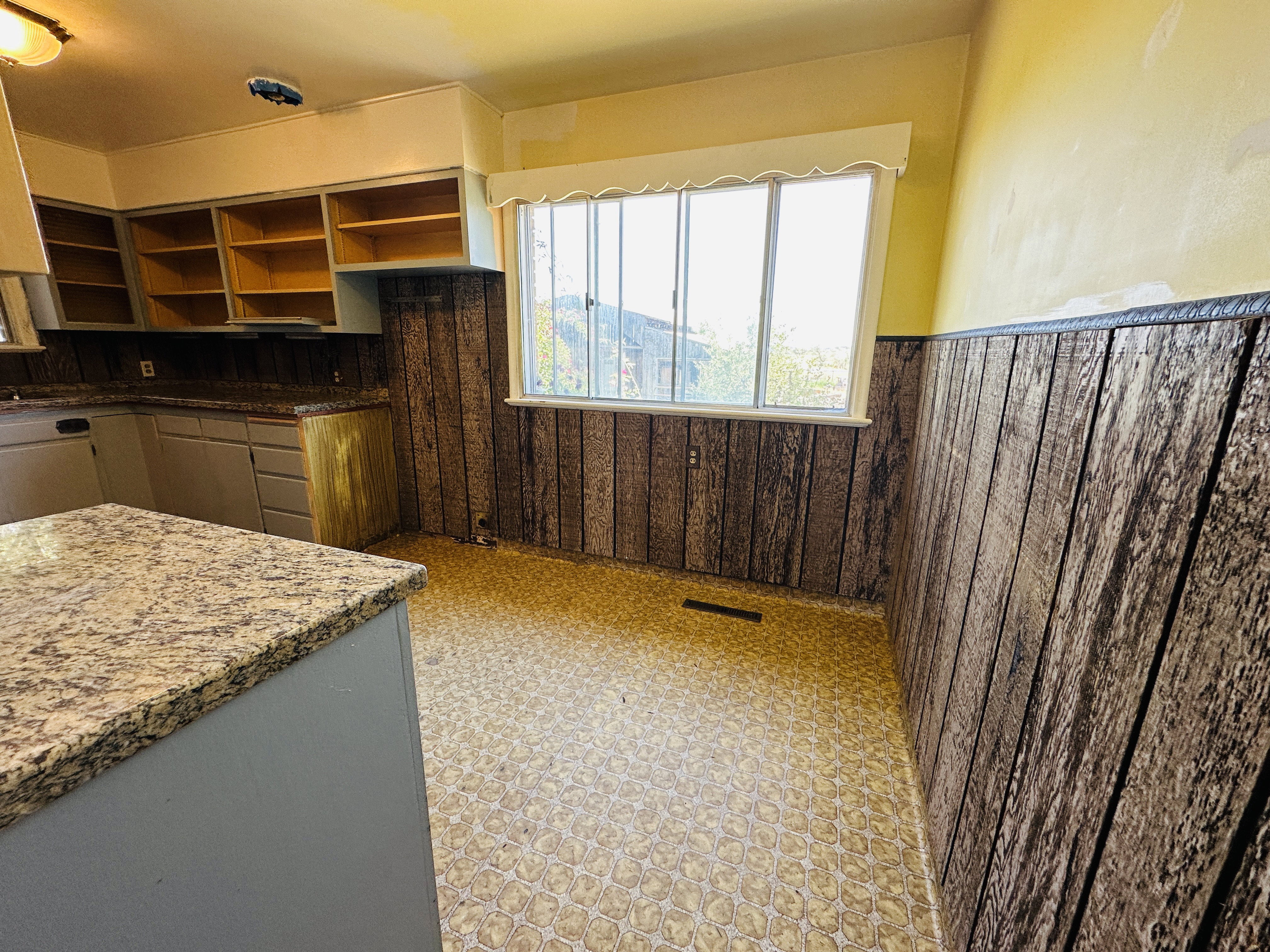 Kitchen featuring a window, built-in cabinetry, and wood-finish wall paneling