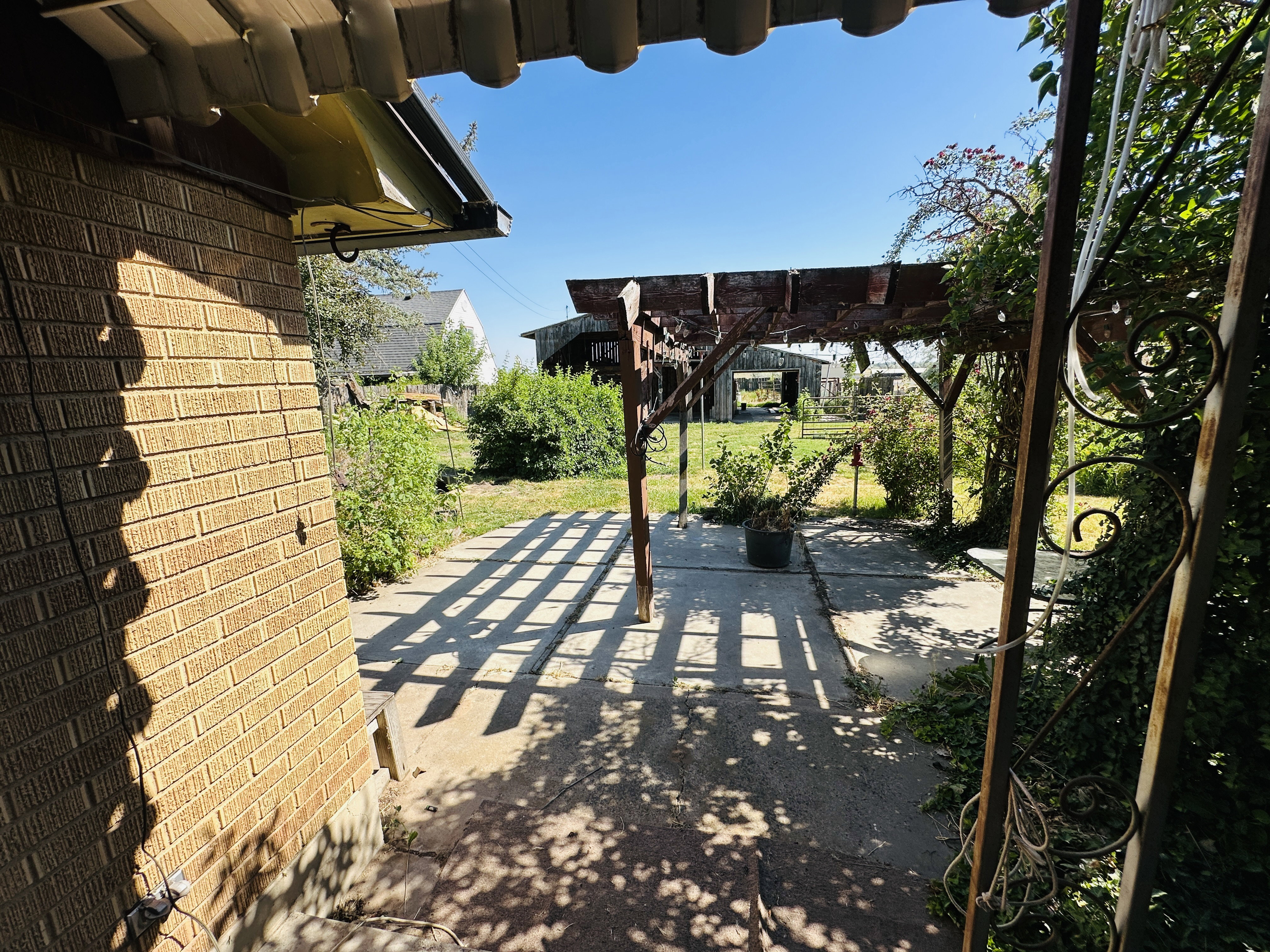 Exterior brick facade with a concrete patio featuring a wooden pergola