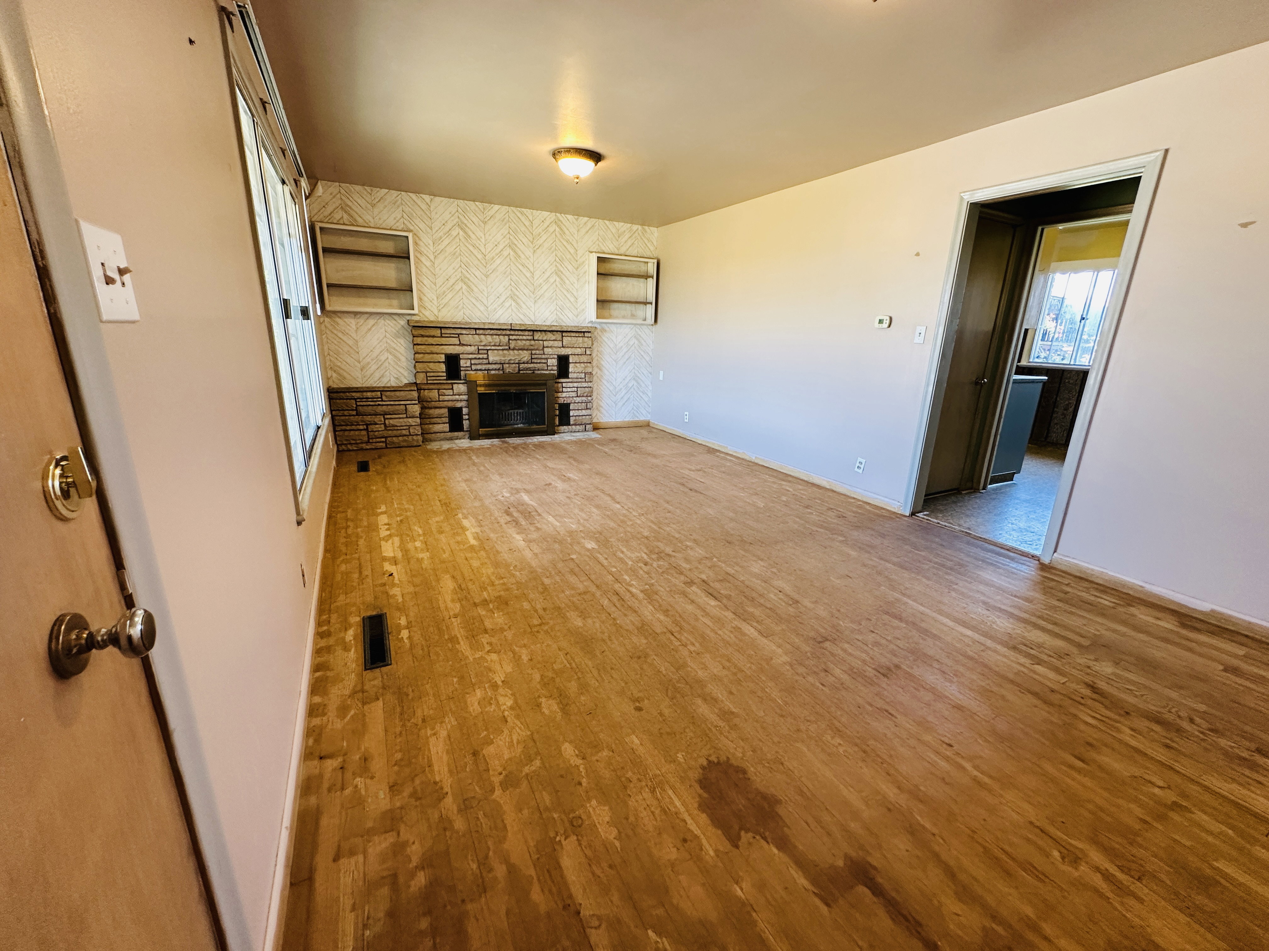 Living area featuring wood-finish flooring, a stone-faced fireplace, and built-in shelving