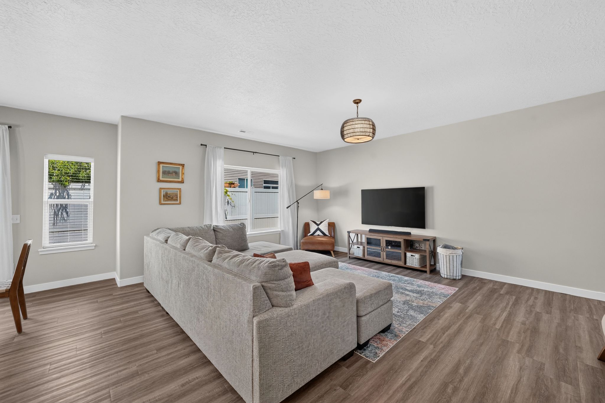 Spacious room featuring wood-finish flooring, light gray walls, and large white-trimmed windows