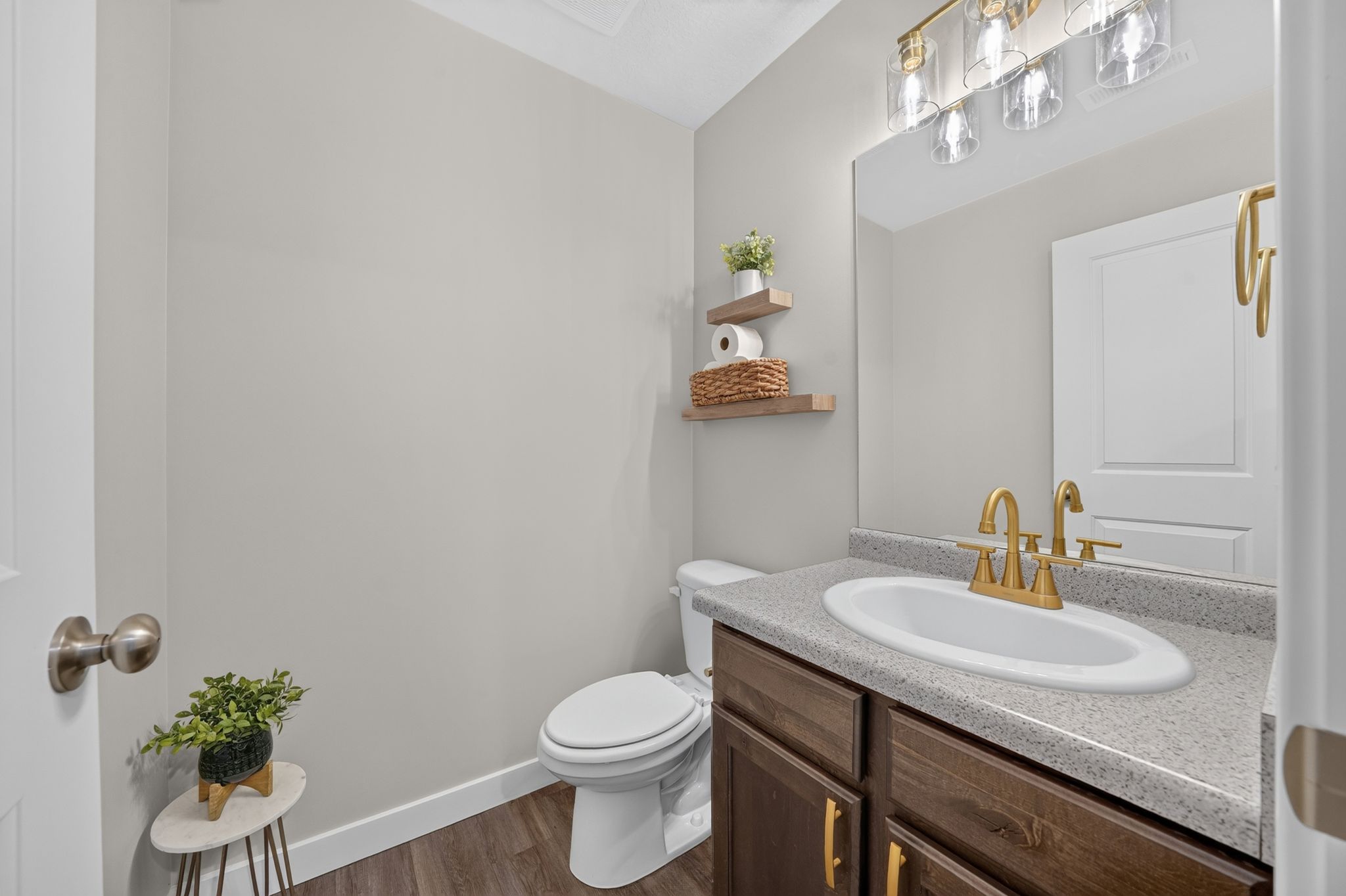 Bathroom featuring a dark wood-finish vanity with a light speckled countertop, an oval undermount sink, and a gold-tone faucet