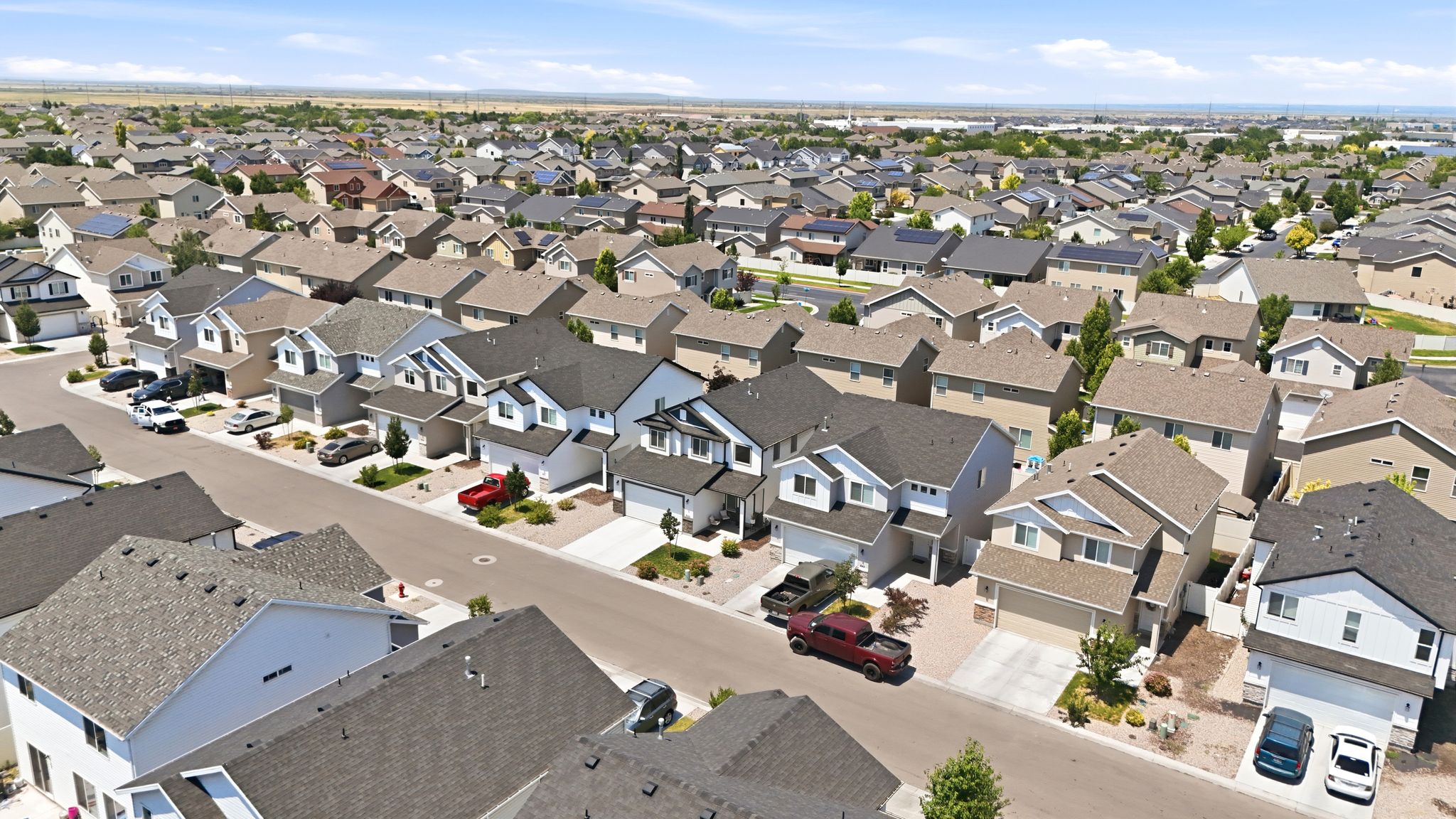 Residential street featuring multiple two-story homes with attached garages, shingle roofs, and light-toned siding