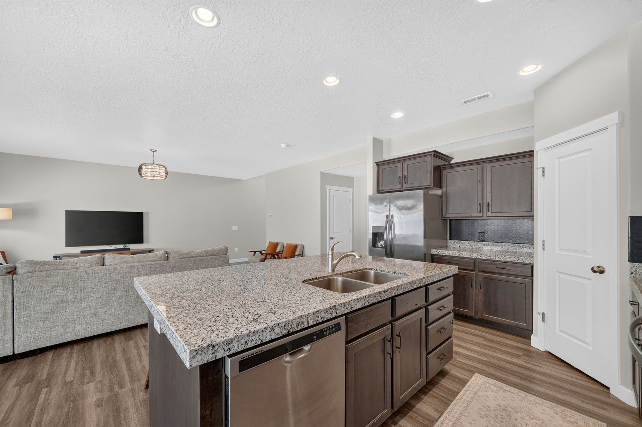 Kitchen island featuring a double-basin sink, stainless steel dishwasher, and a light-toned countertop
