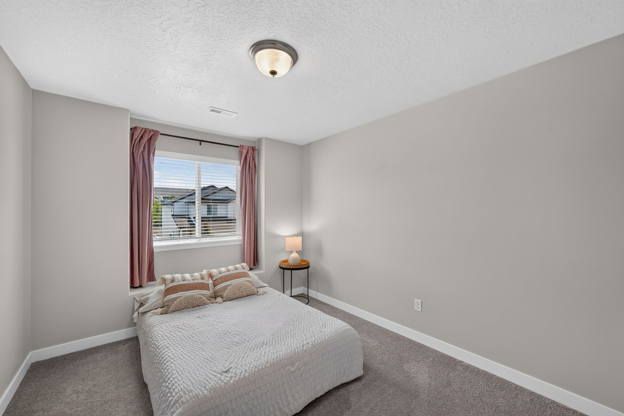 Bedroom featuring a window with blinds, a ceiling-mounted light fixture, light gray walls, white trim, and gray carpet flooring