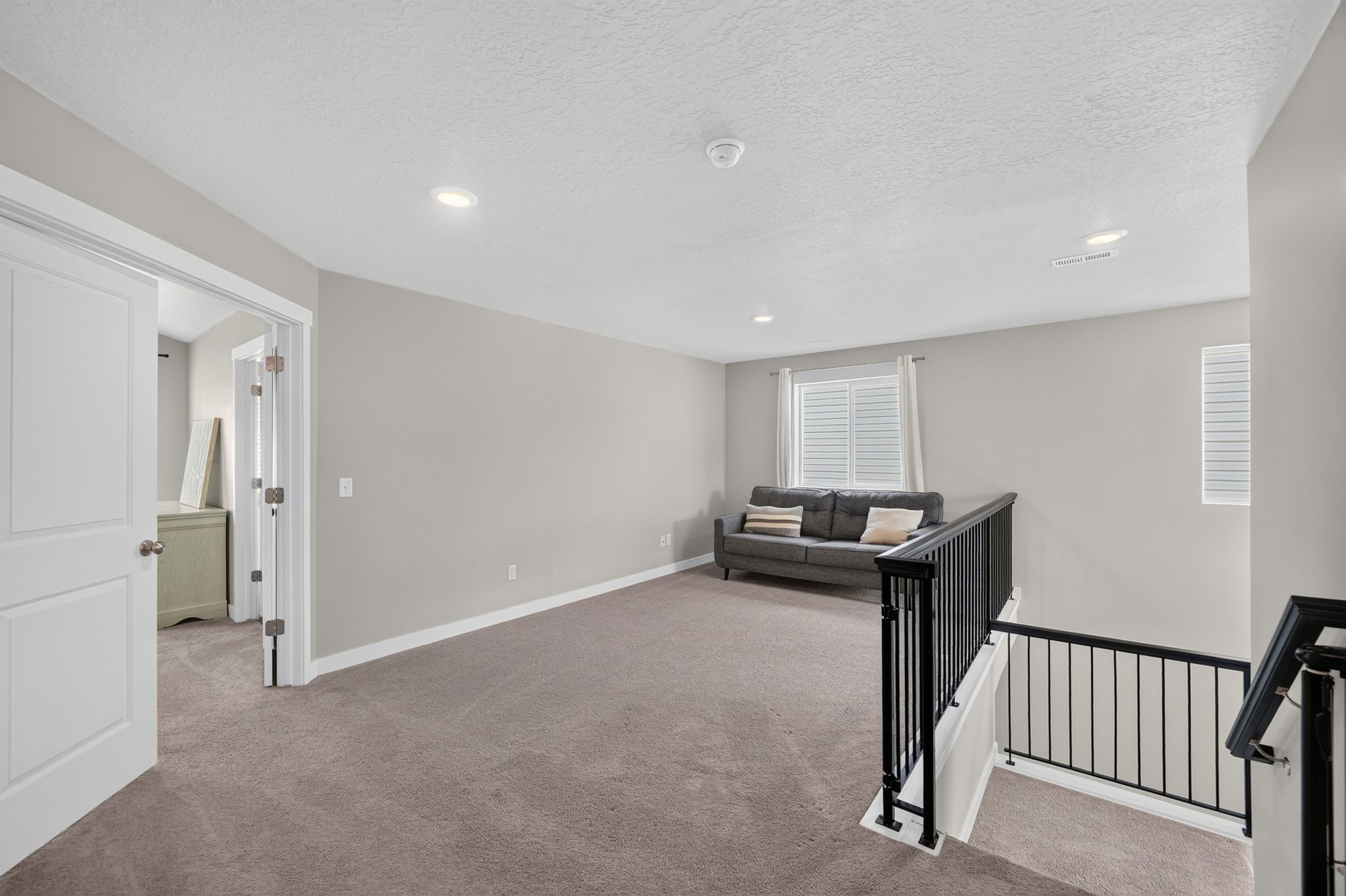 Open loft space featuring neutral carpeting, light gray walls, recessed lighting, and white trim