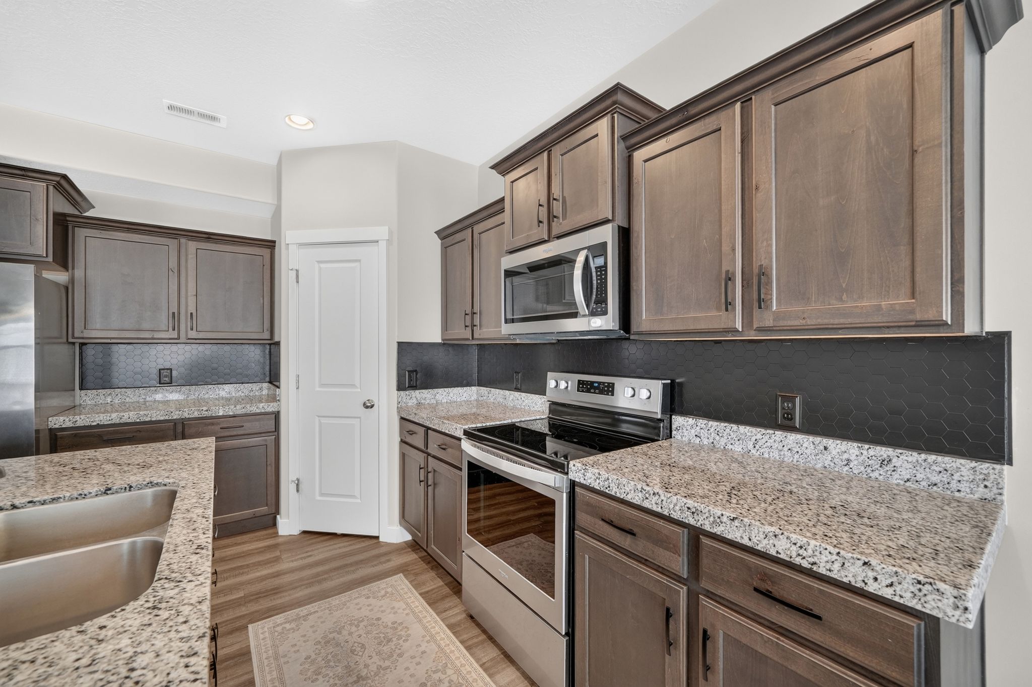 Kitchen featuring wood-finish cabinetry, light-toned countertops, and a black honeycomb-patterned backsplash