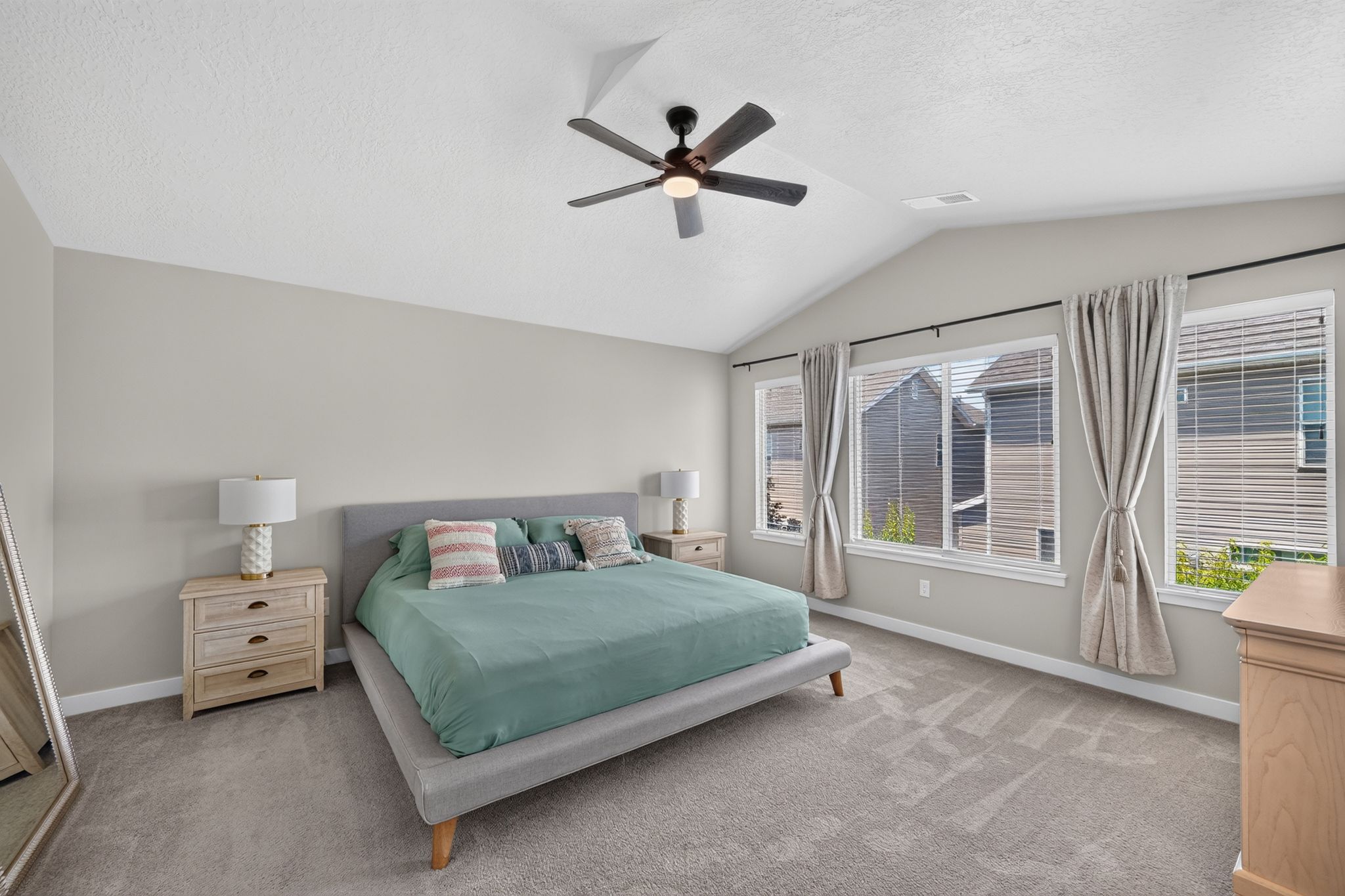 Vaulted ceiling bedroom featuring plush gray carpeting and a modern ceiling fan