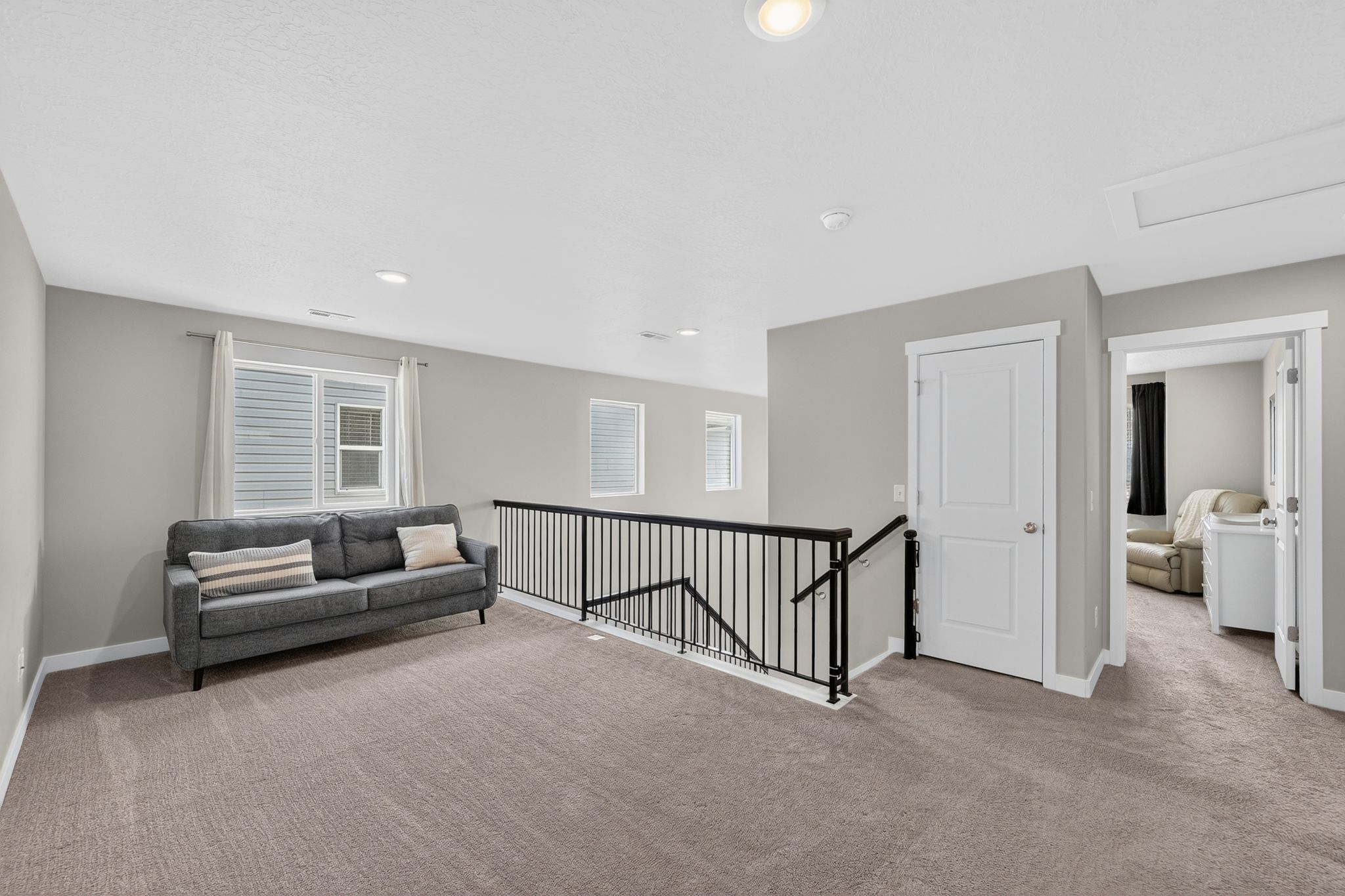 Upper-level landing featuring neutral carpet, light gray walls, and white trim