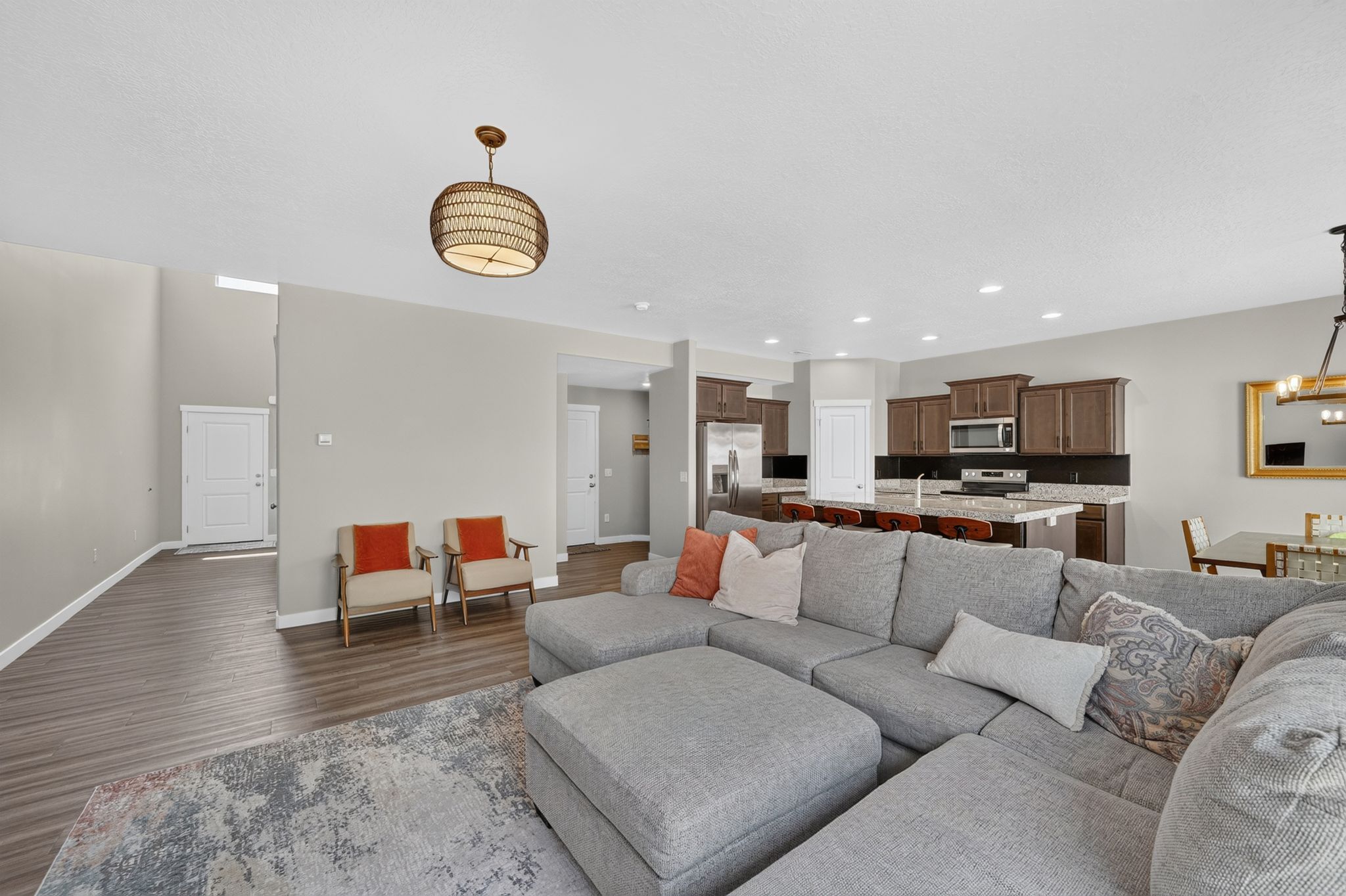 Open-concept living space featuring wood-finish flooring, recessed lighting, and a kitchen with dark cabinetry and a light-toned countertop