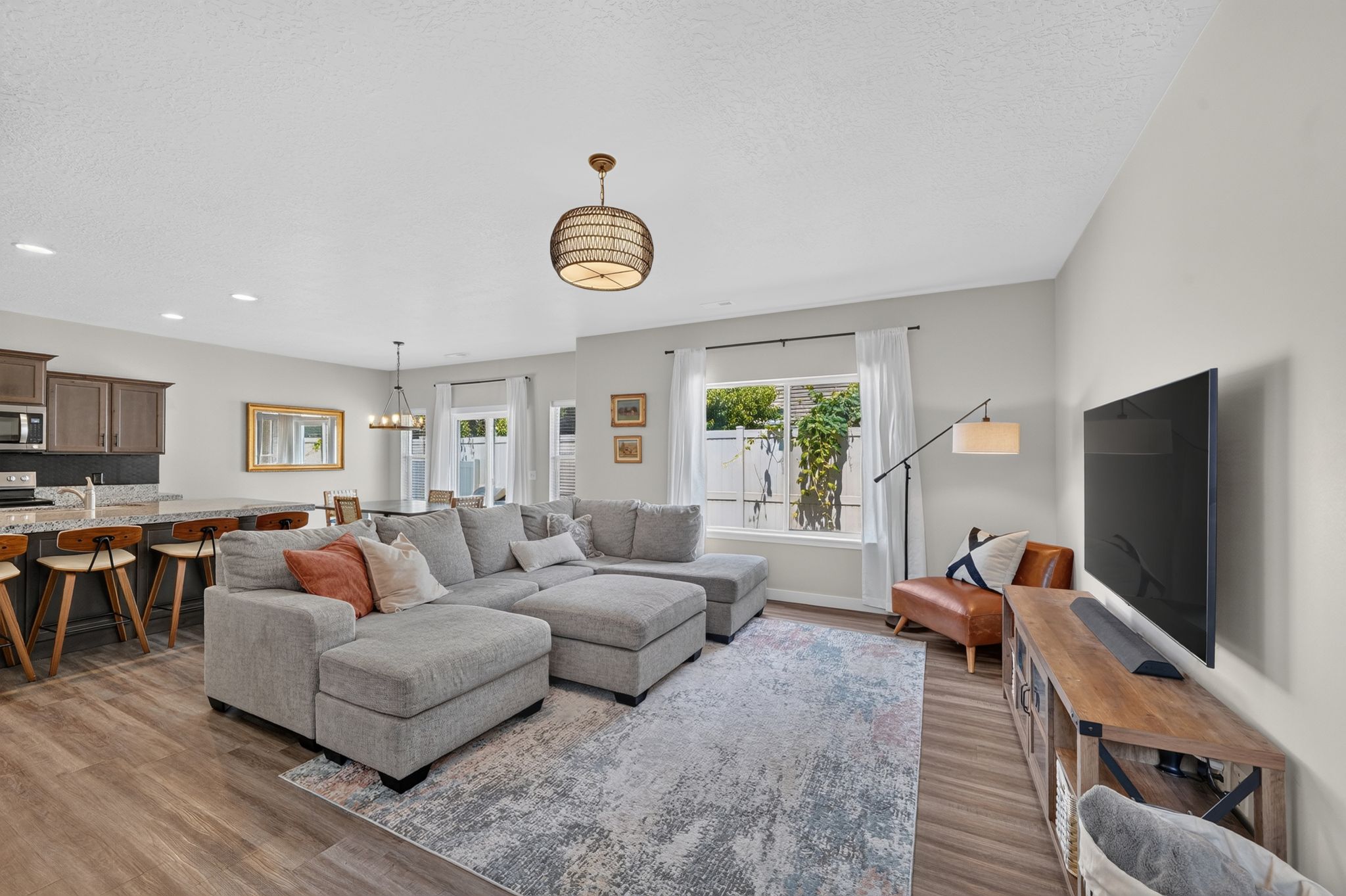 Open-concept living area featuring wood-finish flooring, recessed lighting, and a kitchen island with stone countertops
