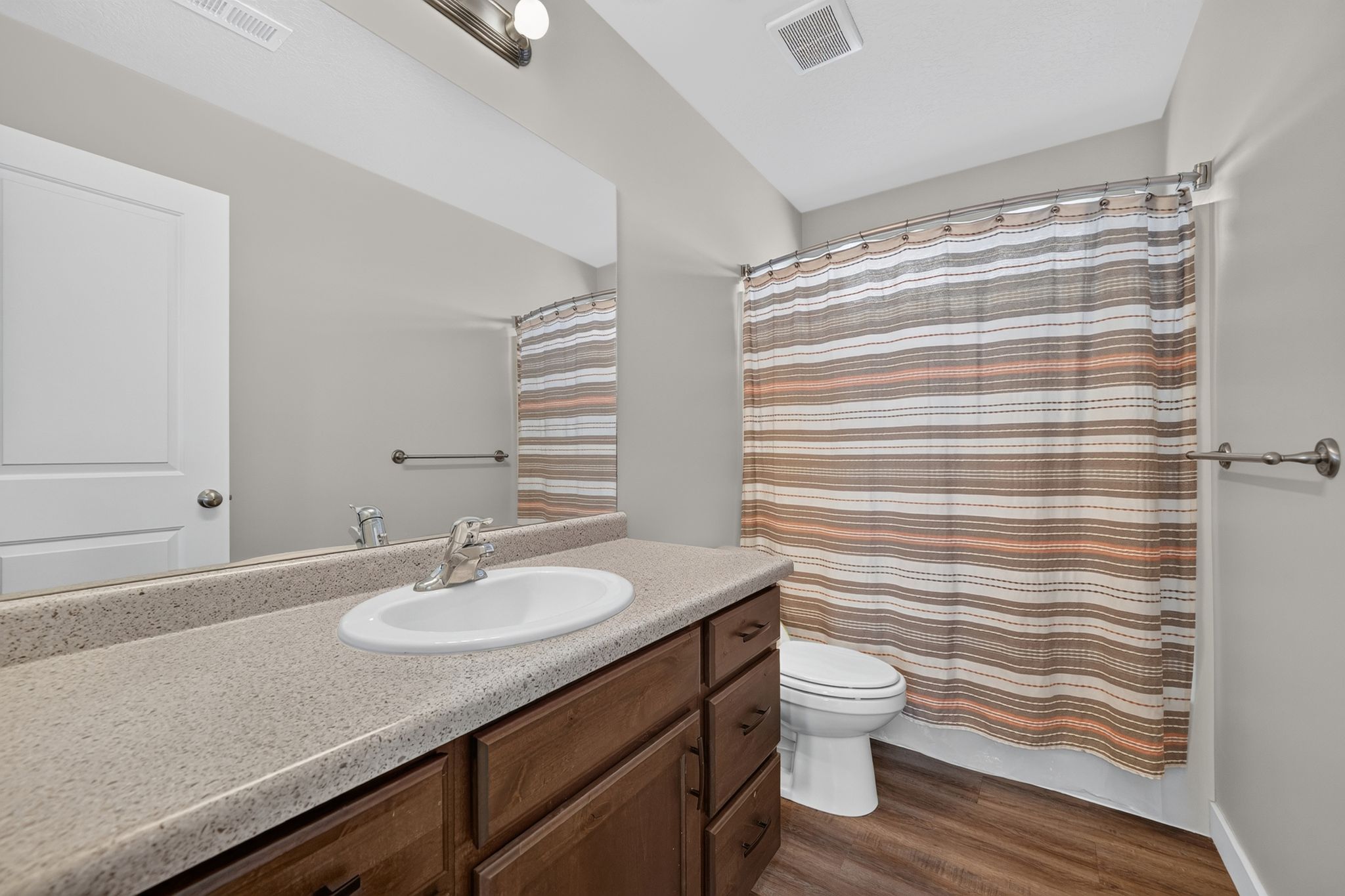 Bathroom featuring a single vanity with an integrated sink, a speckled countertop, and wood-finish cabinetry