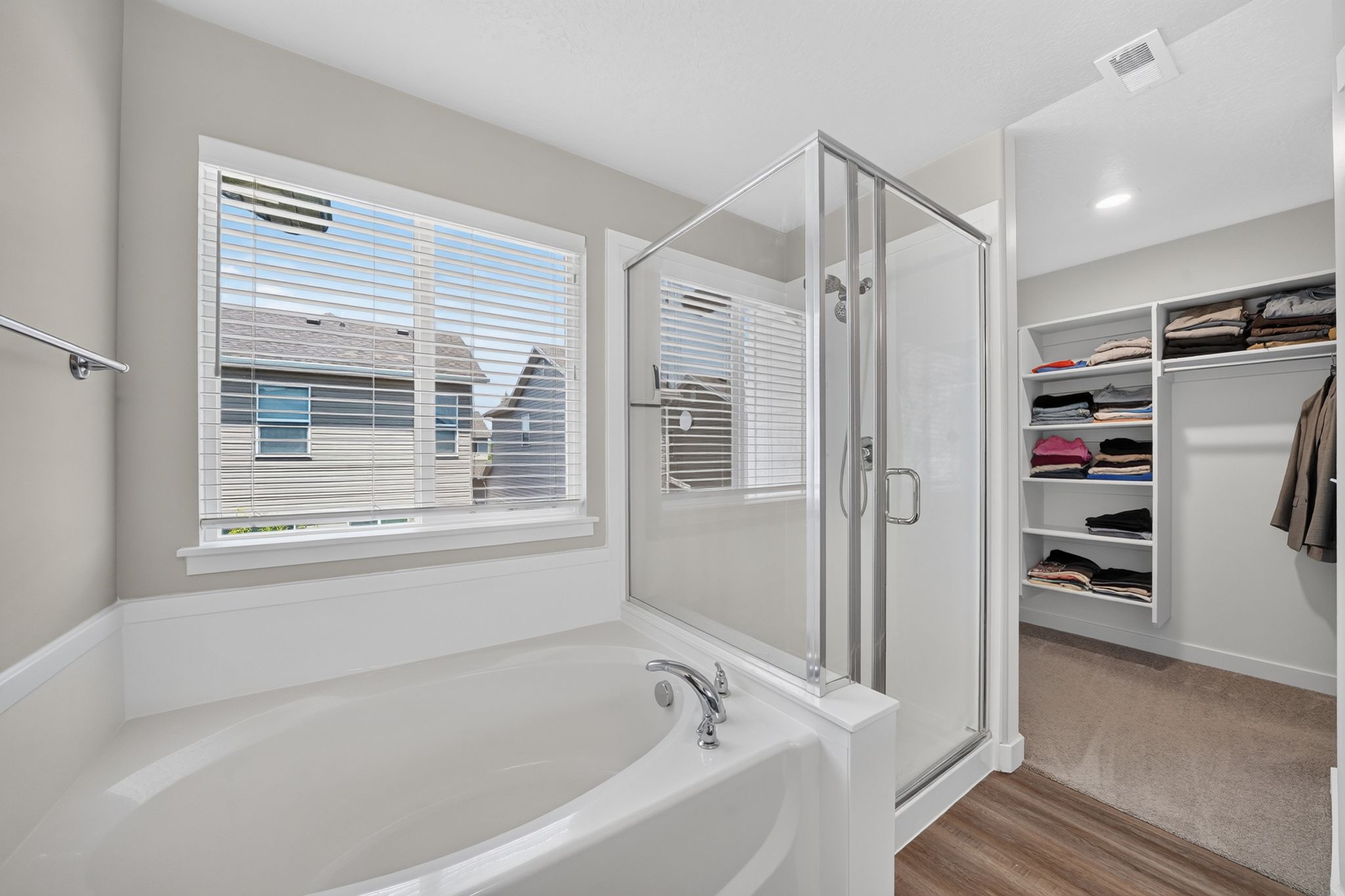 Soaking tub with chrome fixtures and an adjacent glass-enclosed shower