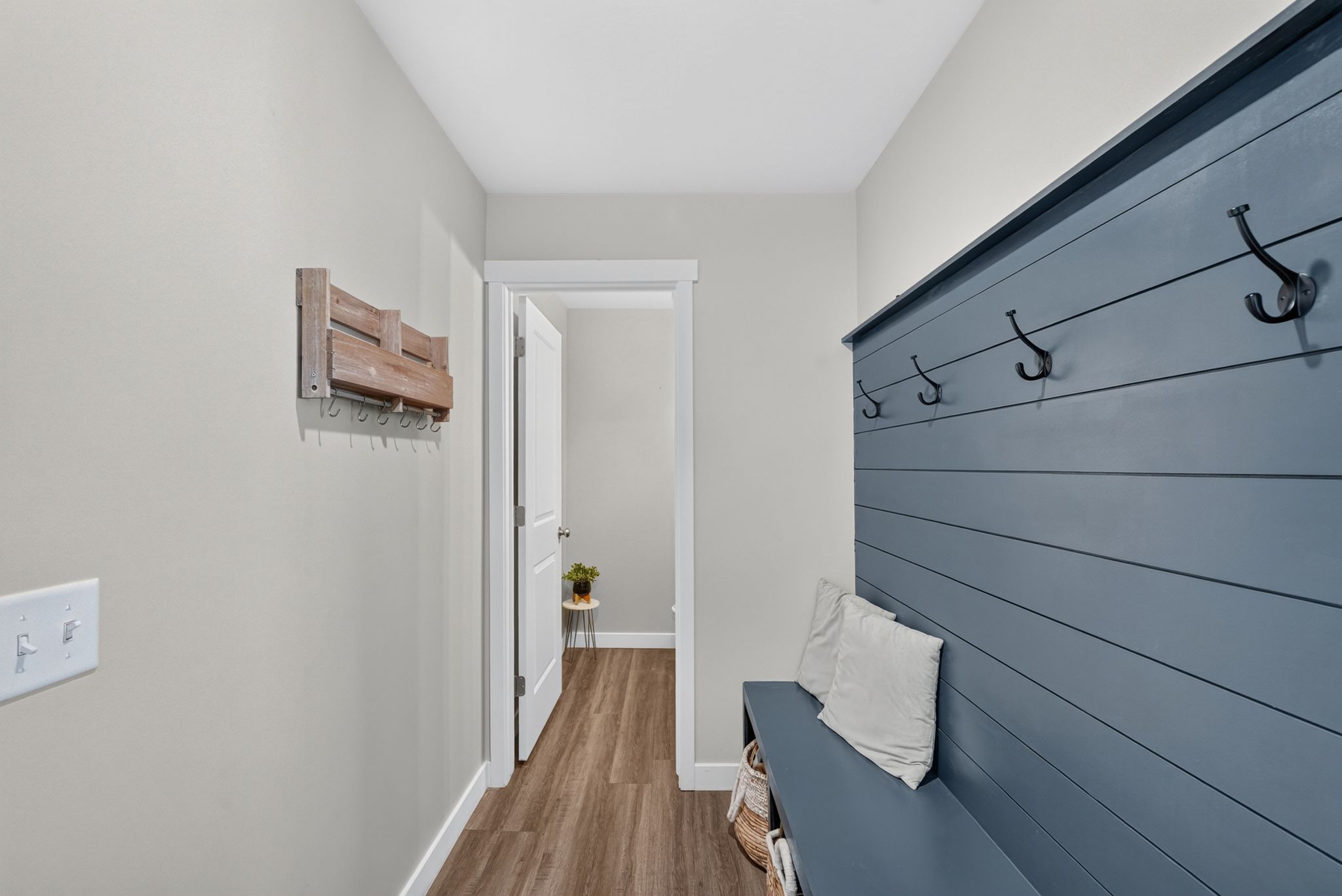 Entryway featuring a built-in bench with storage, shiplap wall accent, and five black coat hooks