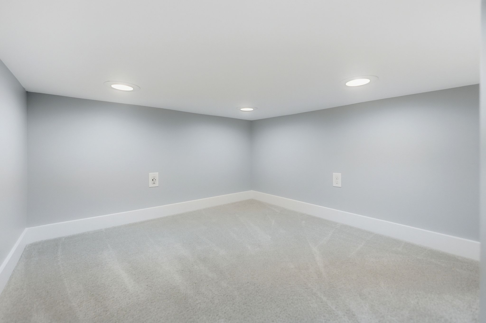 Carpeted interior space featuring light gray walls, white baseboards, and recessed ceiling lighting