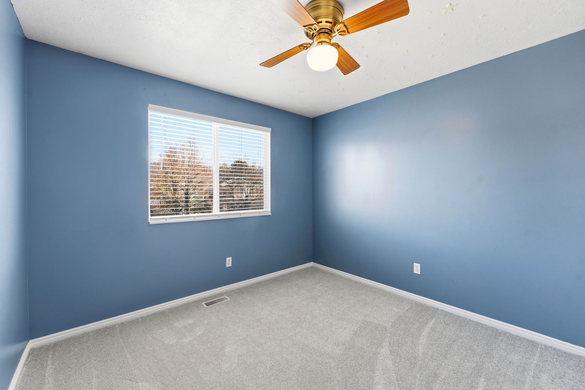 Room featuring carpet flooring, a window with blinds, and a brass-finish ceiling fan with integrated lighting
