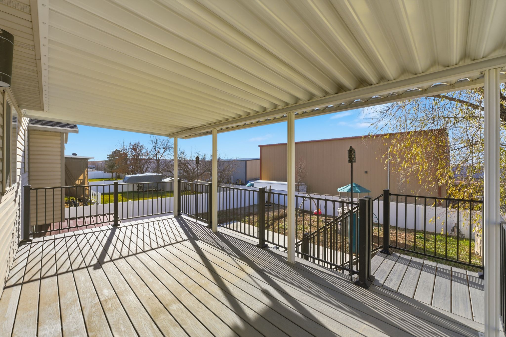 Covered deck featuring composite wood-finish flooring and black metal railings