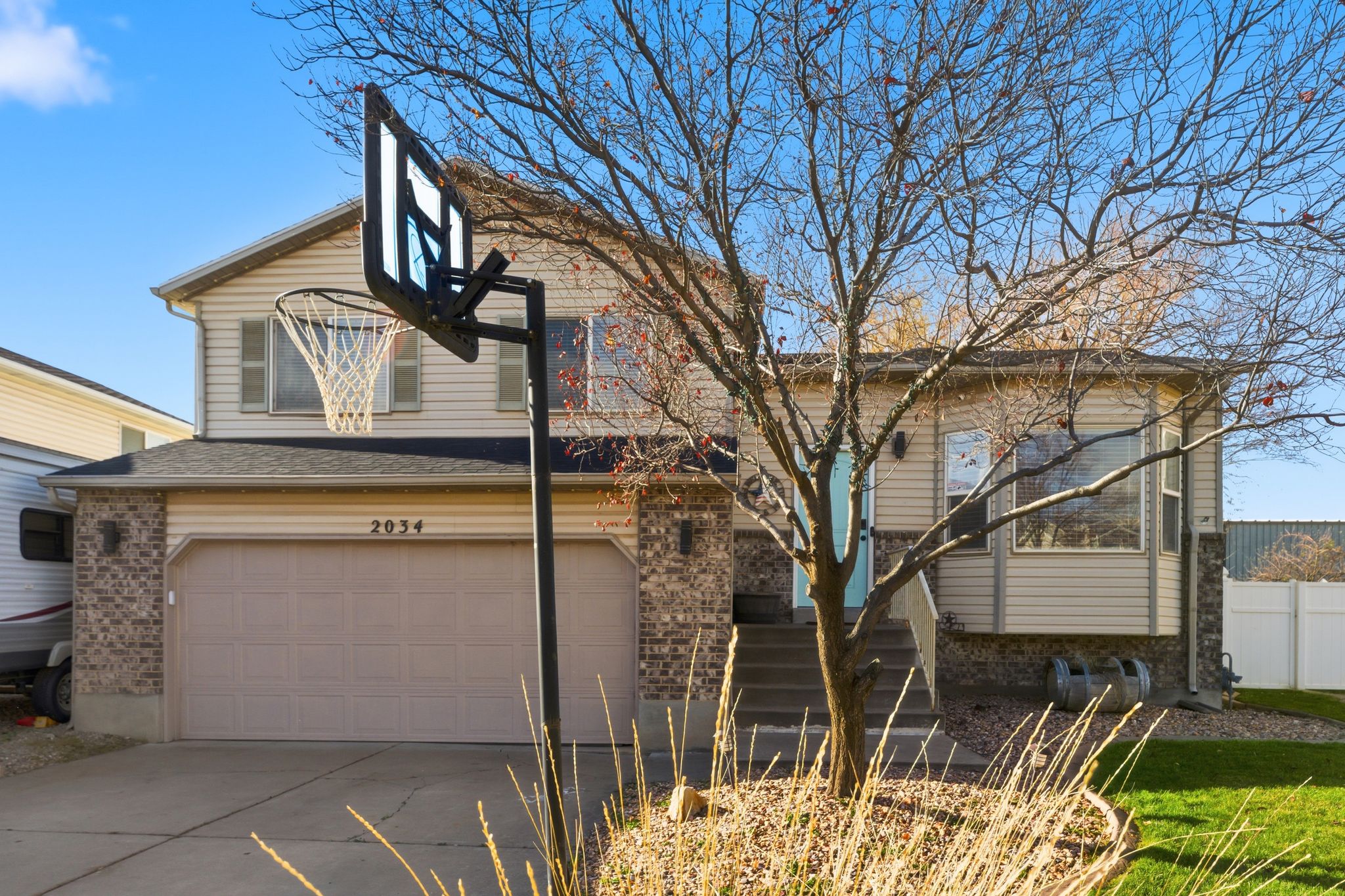 Split-level residence featuring a two-car garage with an integrated address, brick and siding exterior, and a prominent front entrance with stairs