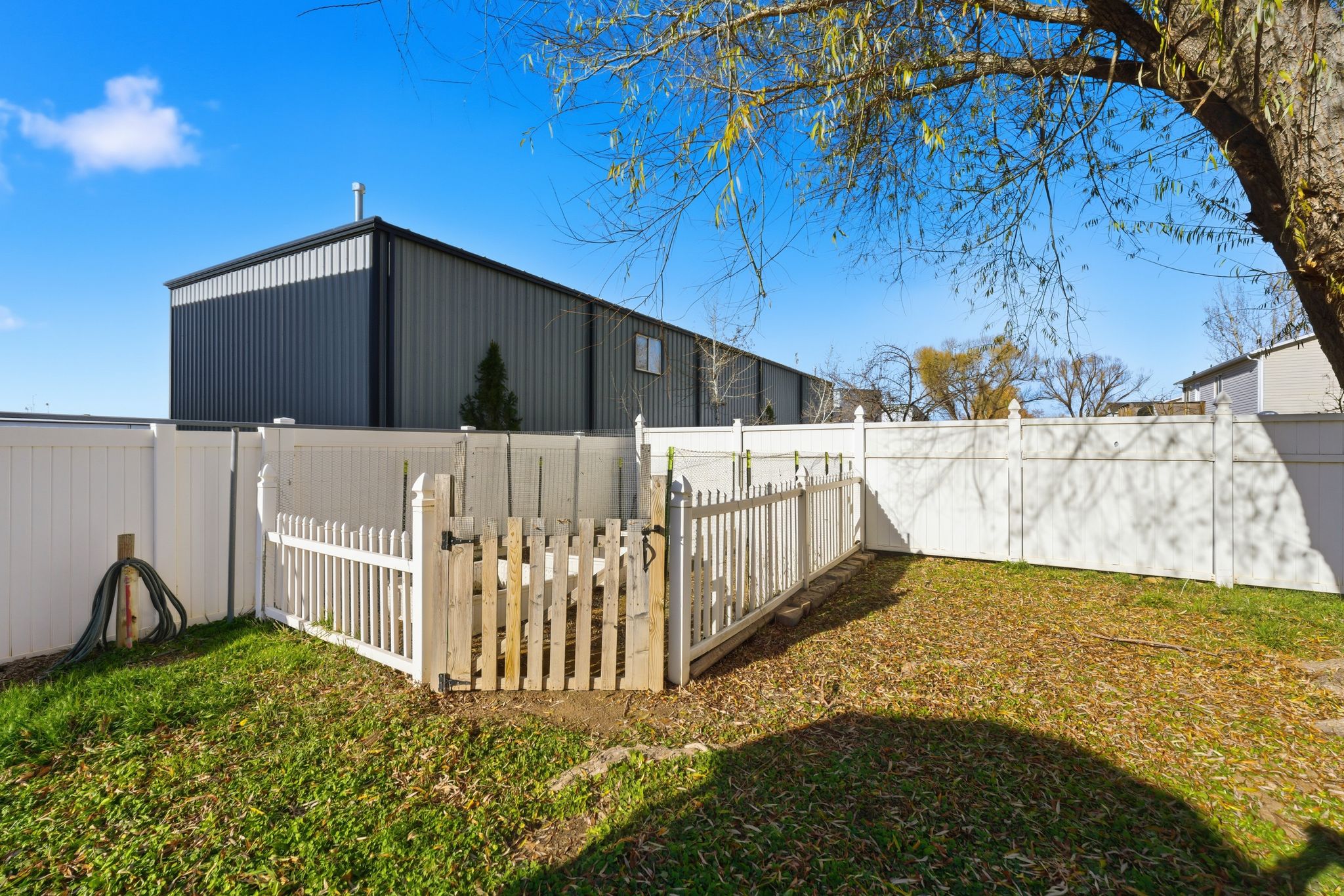 Fenced backyard area featuring a white vinyl fence and a picket fence enclosure