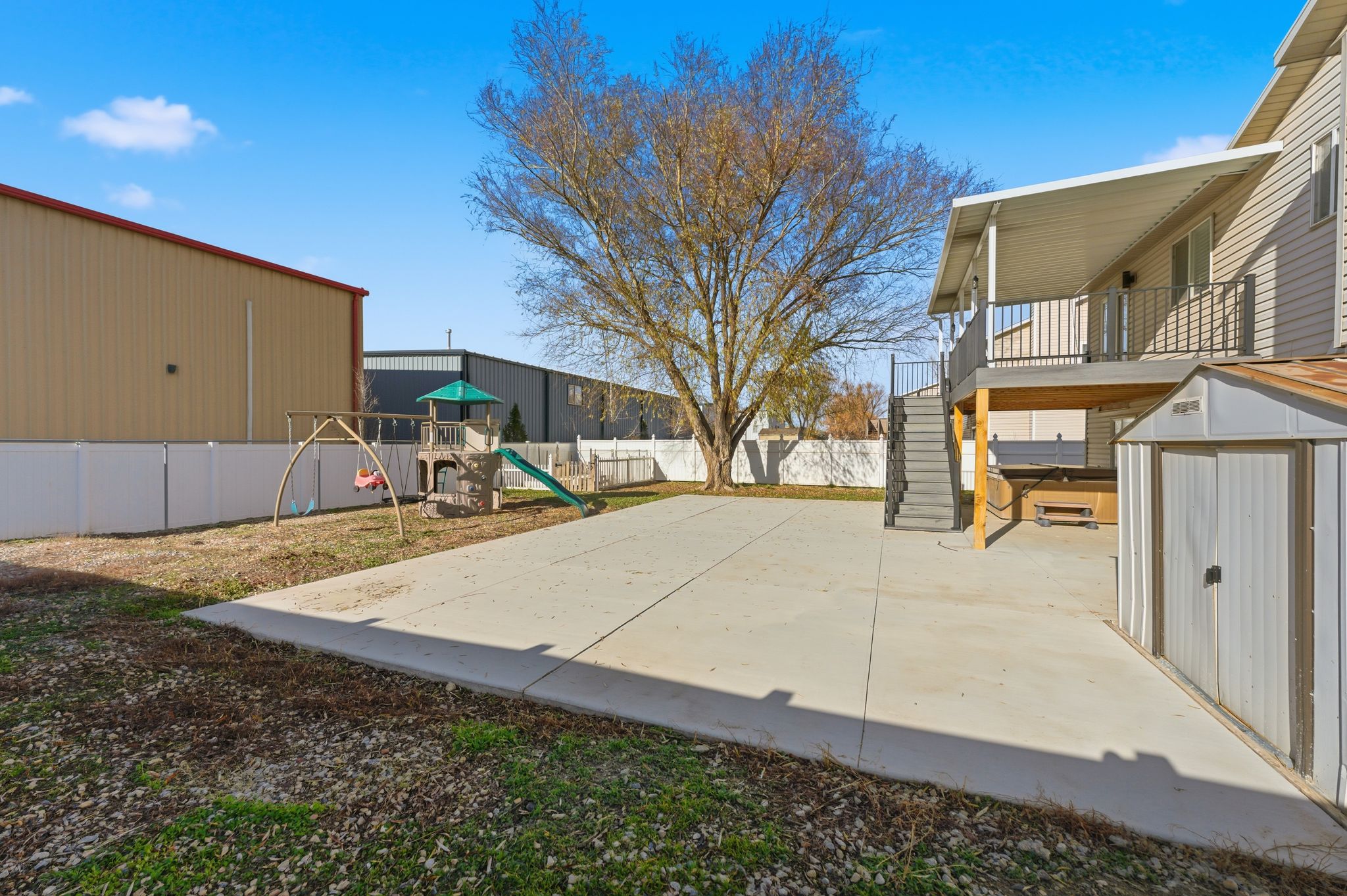 Expansive concrete patio with a covered upper deck featuring black metal railings and exterior stairs
