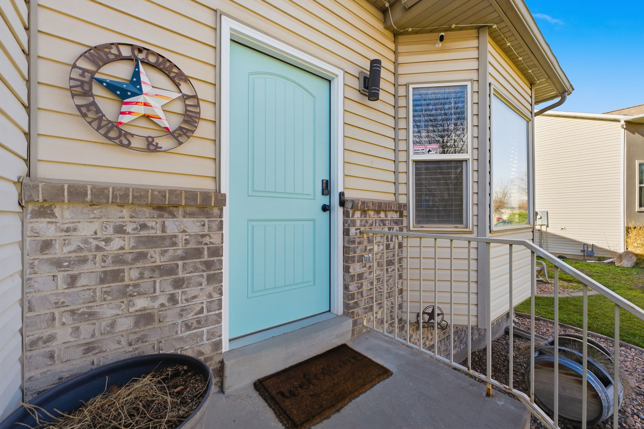 Front entry featuring a light blue door with arched paneling, light-colored horizontal siding, and brick wainscoting