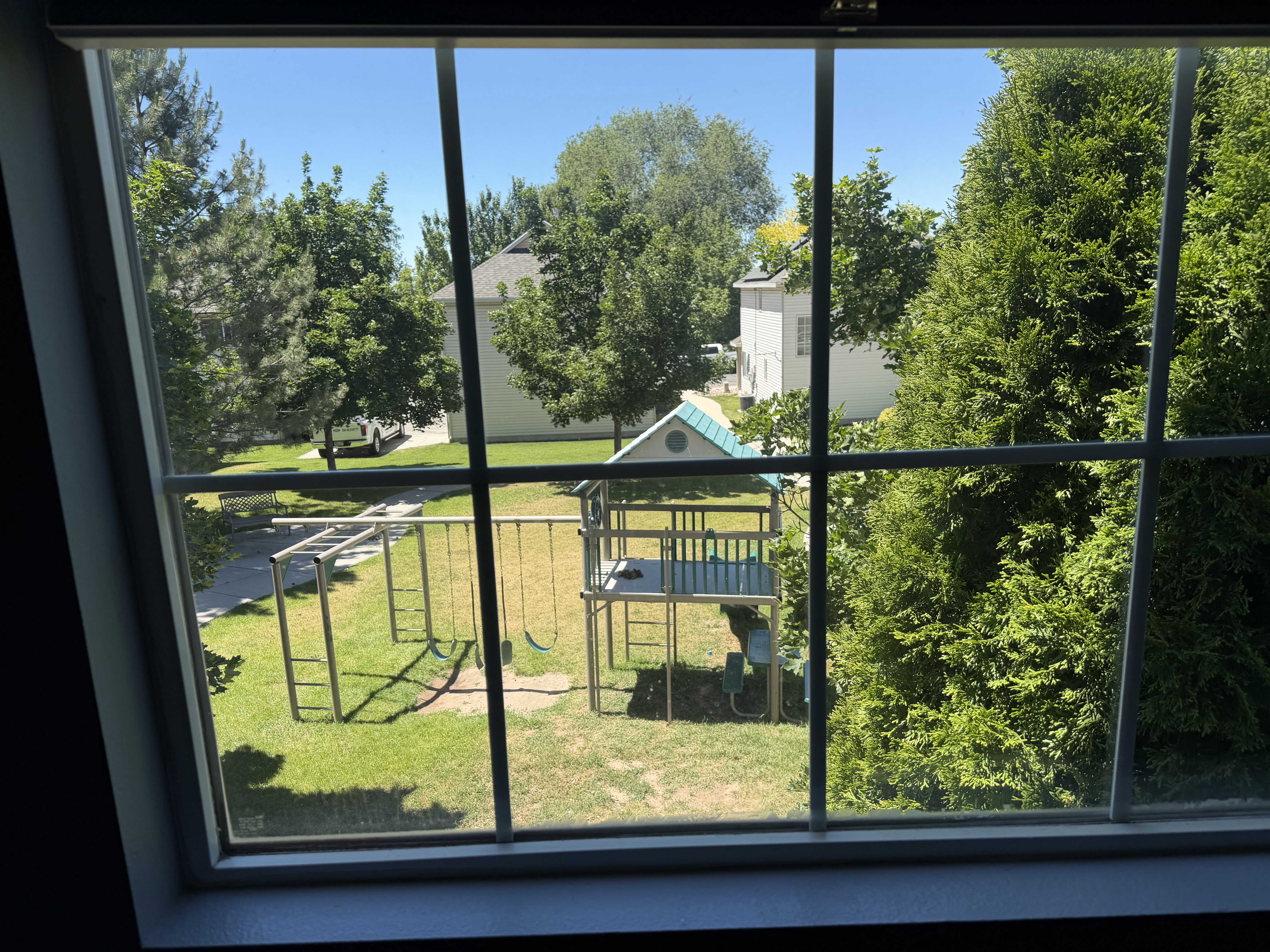 Backyard featuring a play structure with a slide and swings, a separate monkey bar set, and a manicured lawn