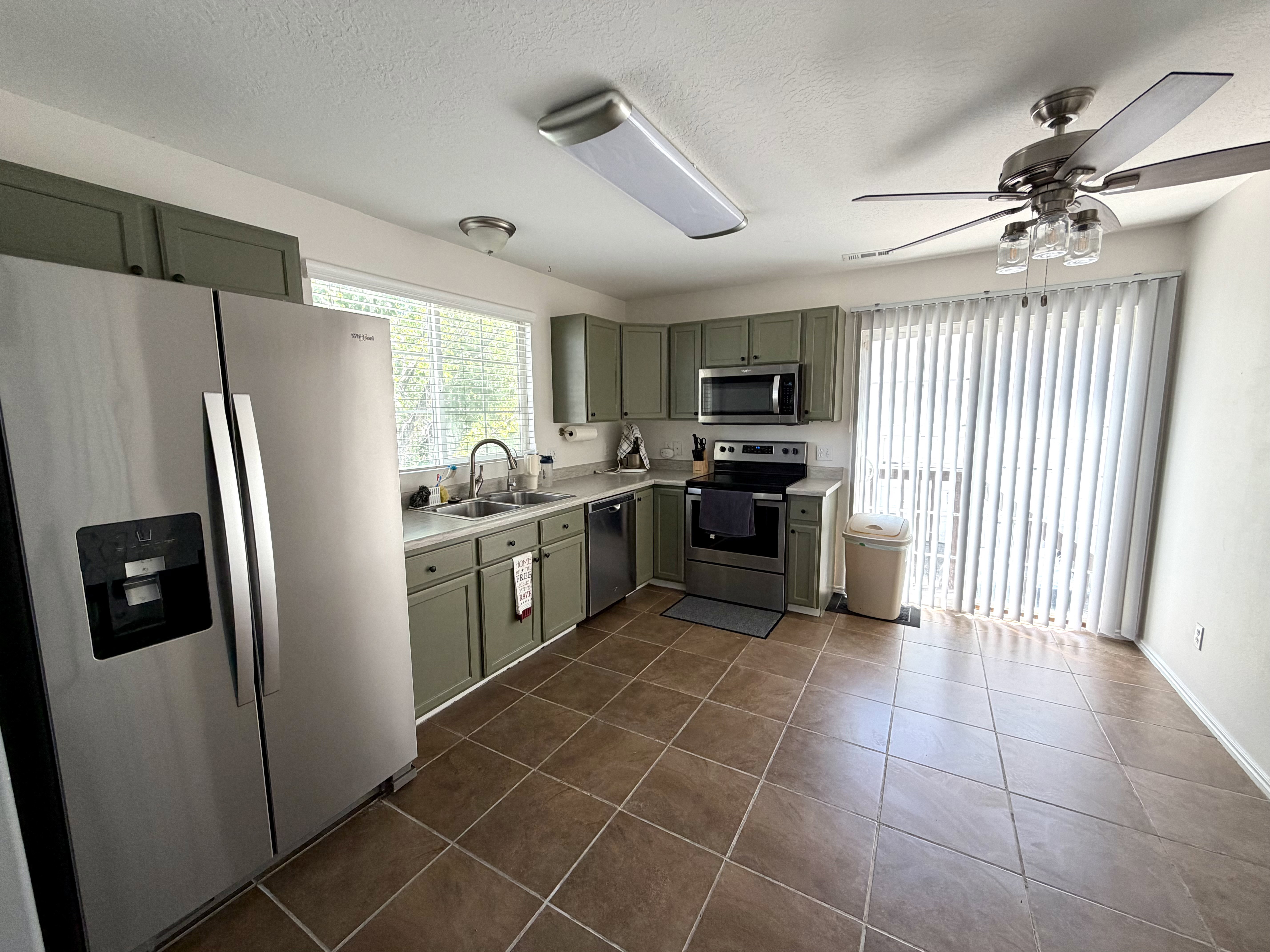 Expansive kitchen featuring stainless steel appliances, ample cabinetry, ceramic tile flooring, and a ceiling fan