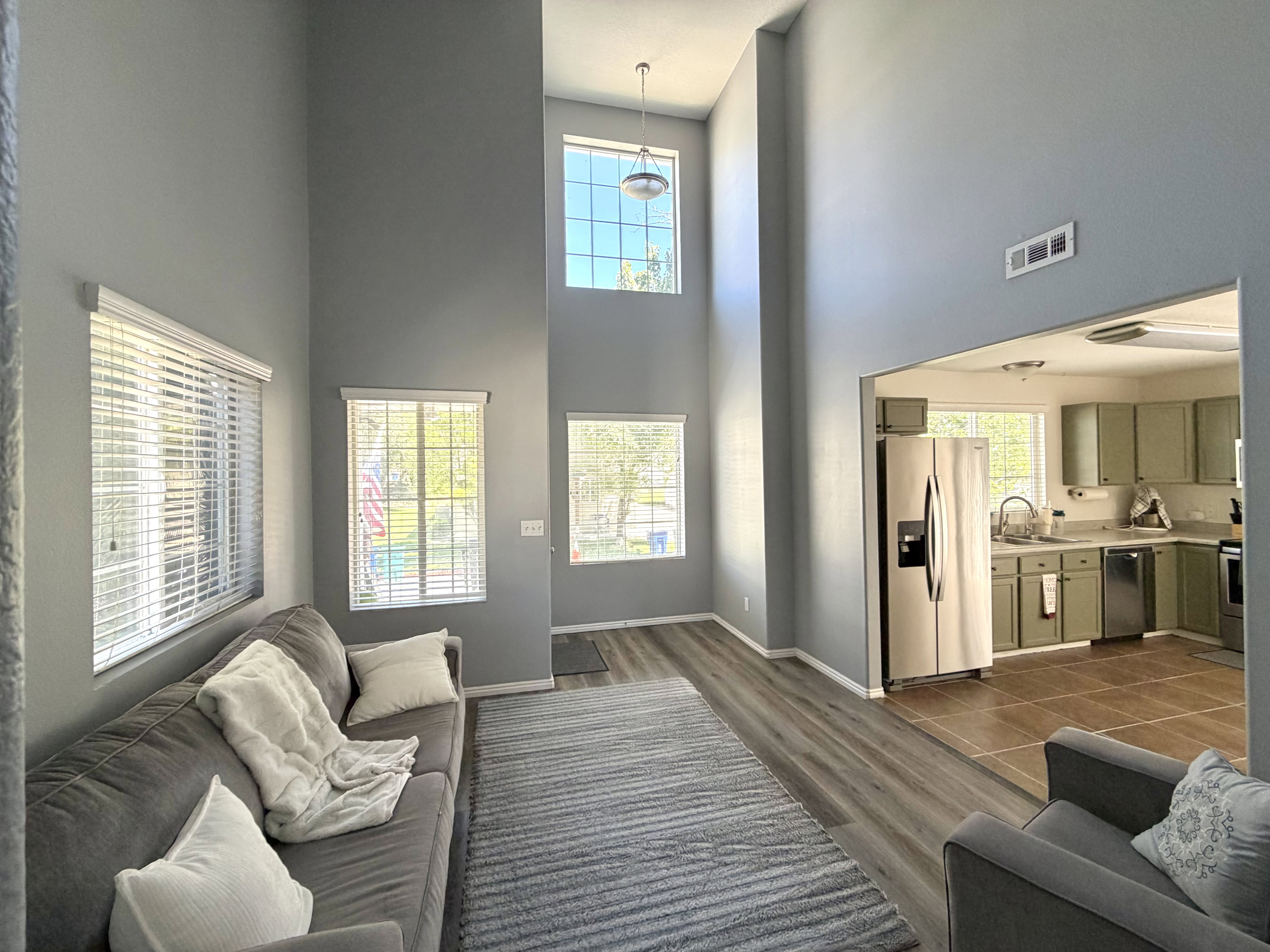 Living area featuring vaulted ceilings, wood-finish flooring, and multiple windows