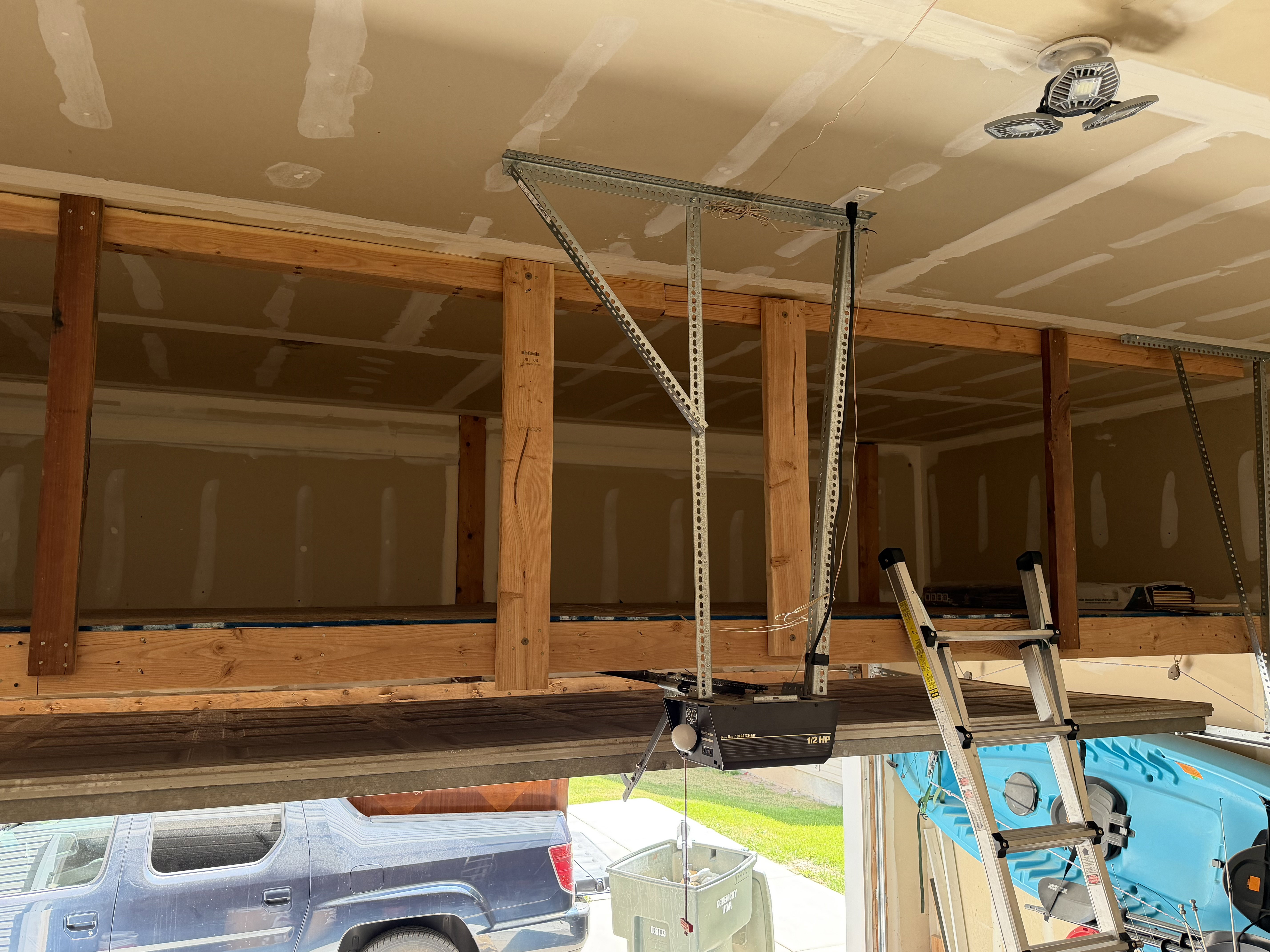 Garage interior featuring built-in overhead storage, exposed wood framing, and a garage door opener