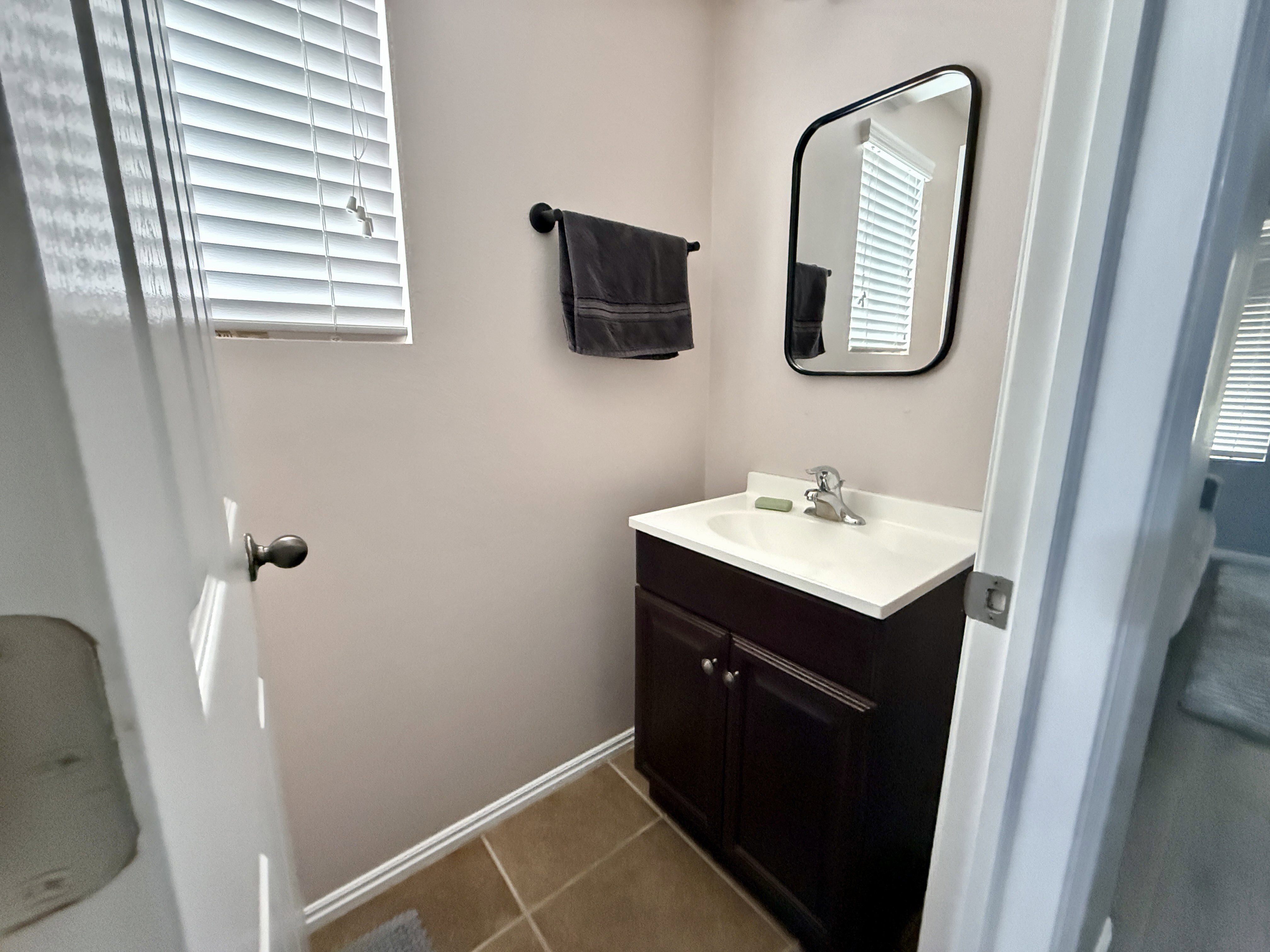 Bathroom vanity featuring a dark wood-finish cabinet with a white countertop and integrated sink