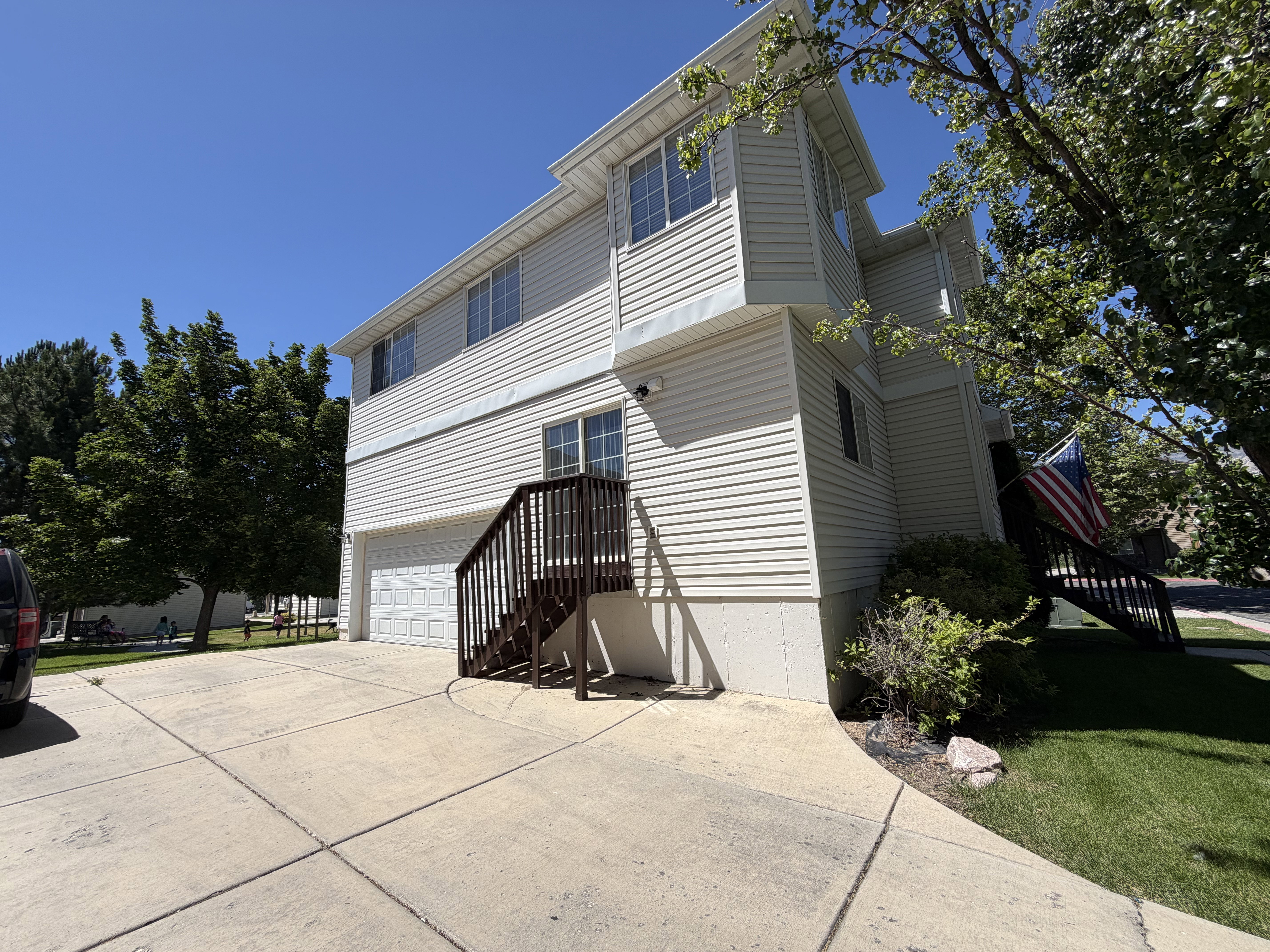 Two-story residence featuring light-colored siding, multiple windows, and a two-car garage