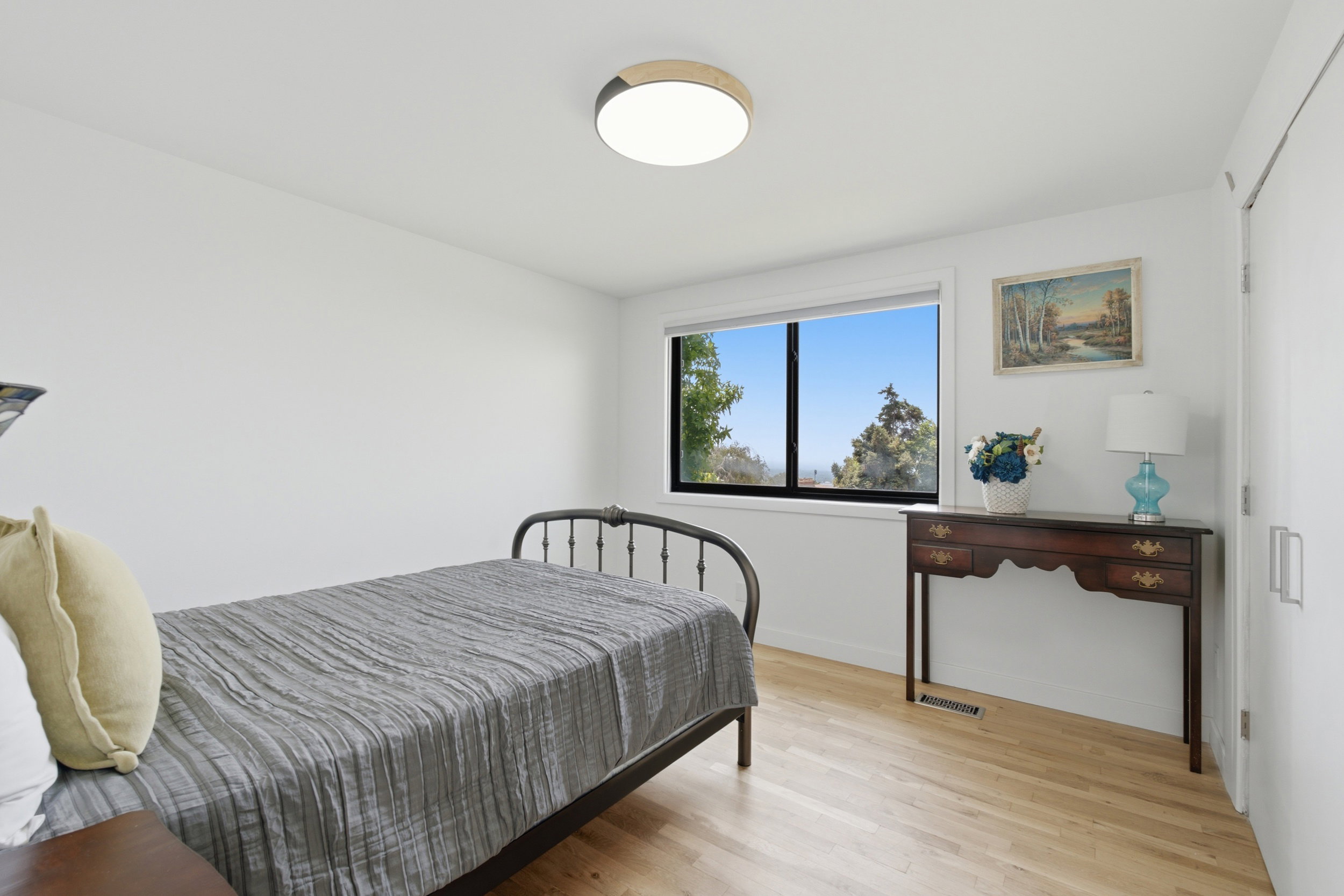 Light wood-finish flooring with white walls and a large window