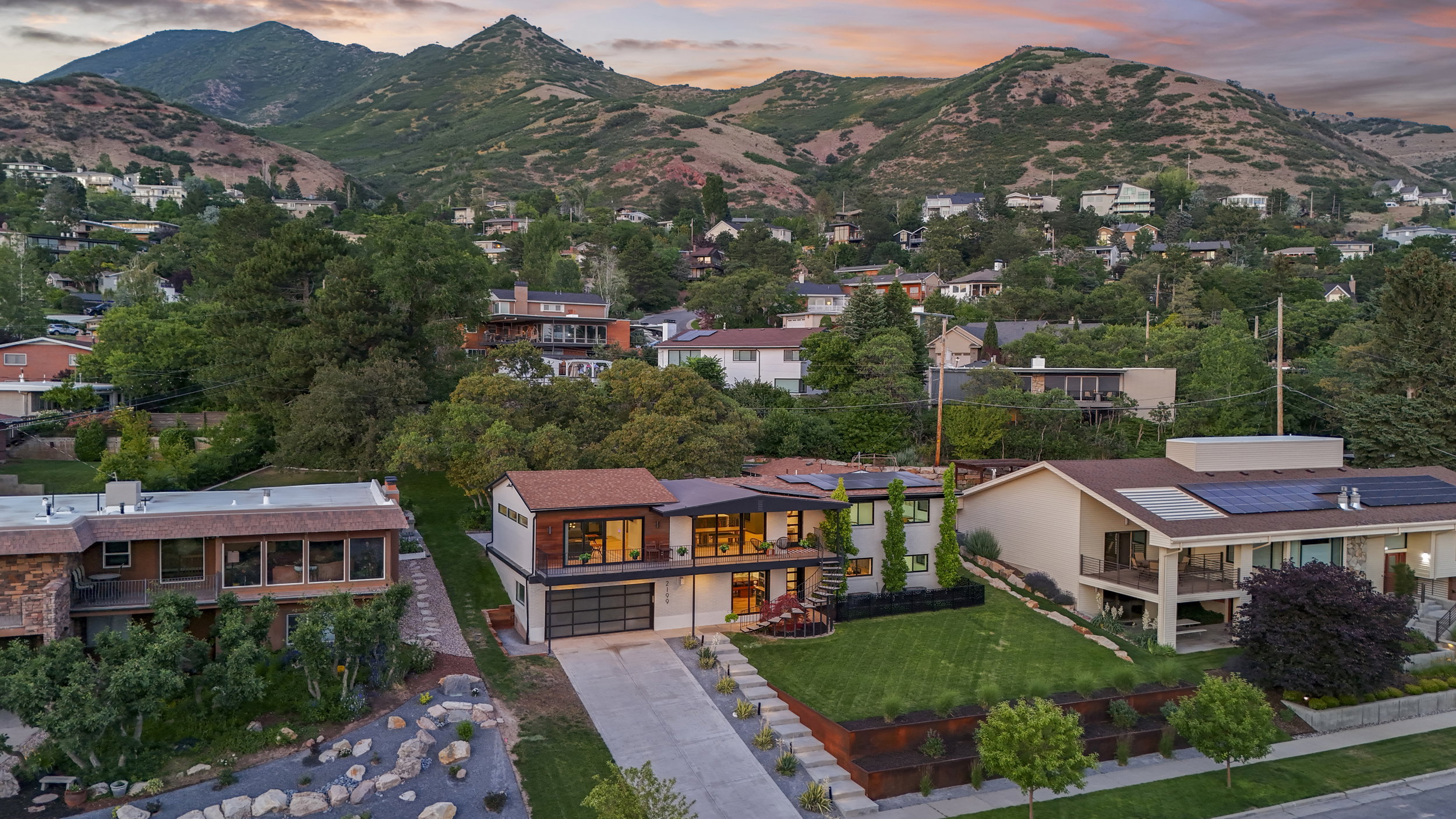 Contemporary architecture with extensive glazing, a two-car garage, and a tiered landscaped front yard