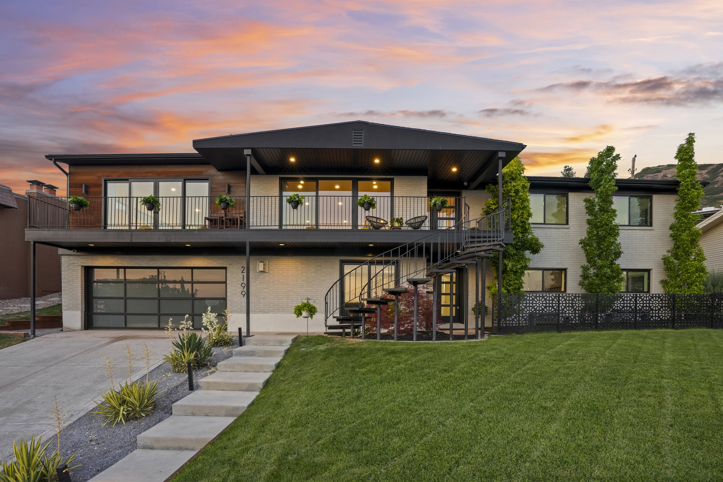 Contemporary multi-level residence featuring a spiral staircase, expansive upper-level balcony, and a modern glass garage door