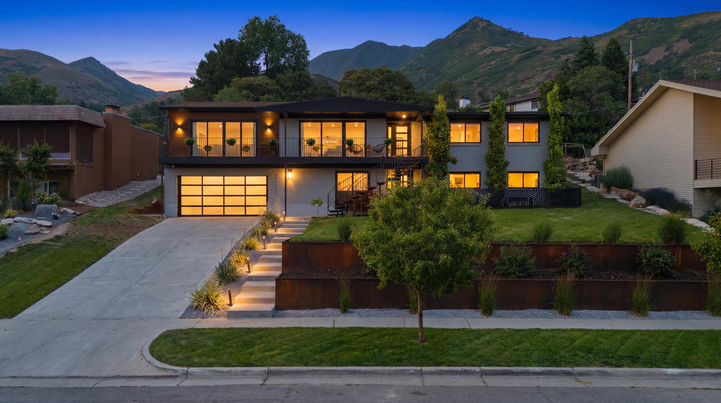 Contemporary exterior featuring a full glass garage door, multi-level windows, and integrated exterior lighting