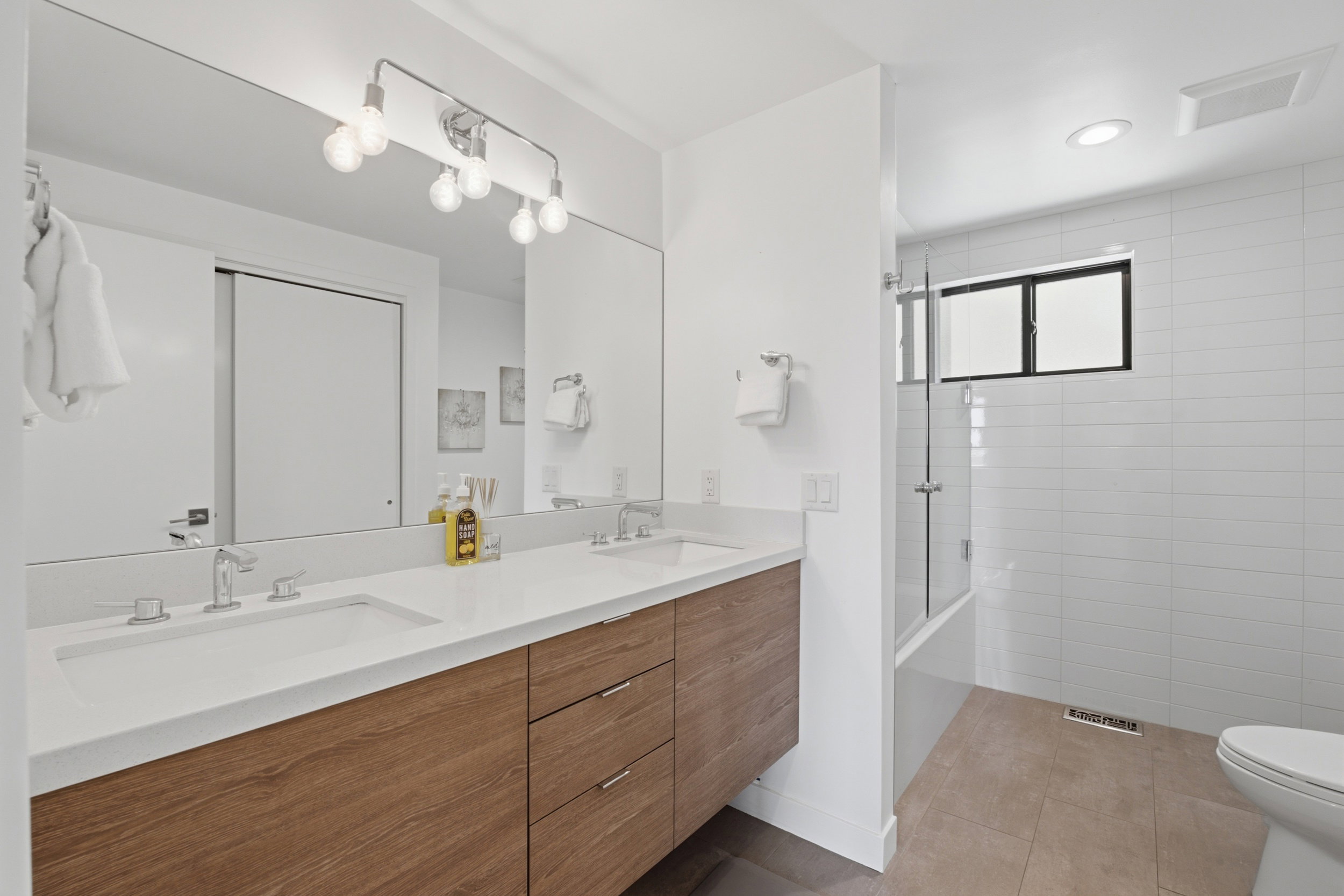 Bathroom featuring a dual vanity with wood-finish cabinetry, white countertops, and chrome fixtures