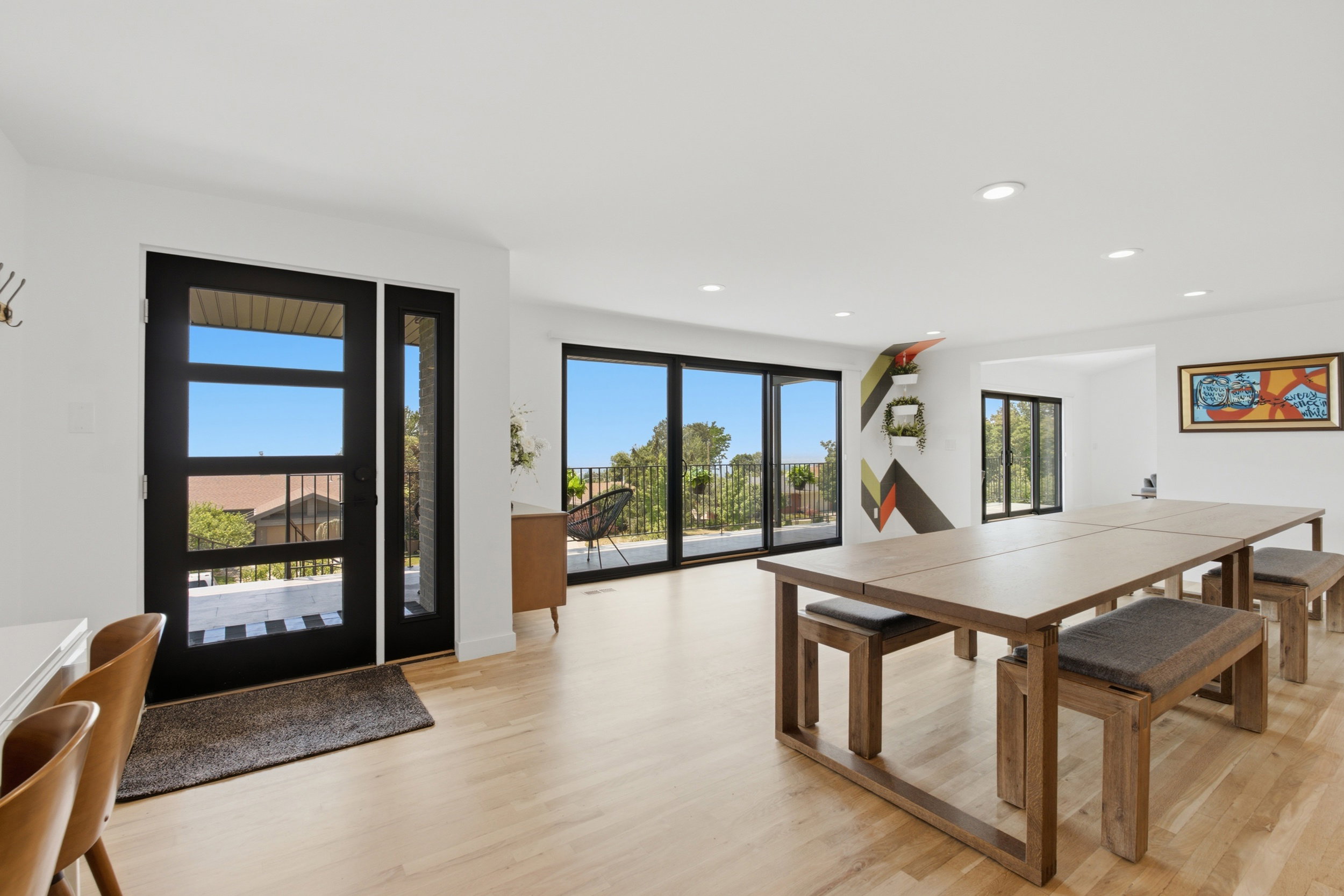 Spacious room featuring light wood-finish flooring, recessed lighting, and a black-framed glass entry door with a sidelight