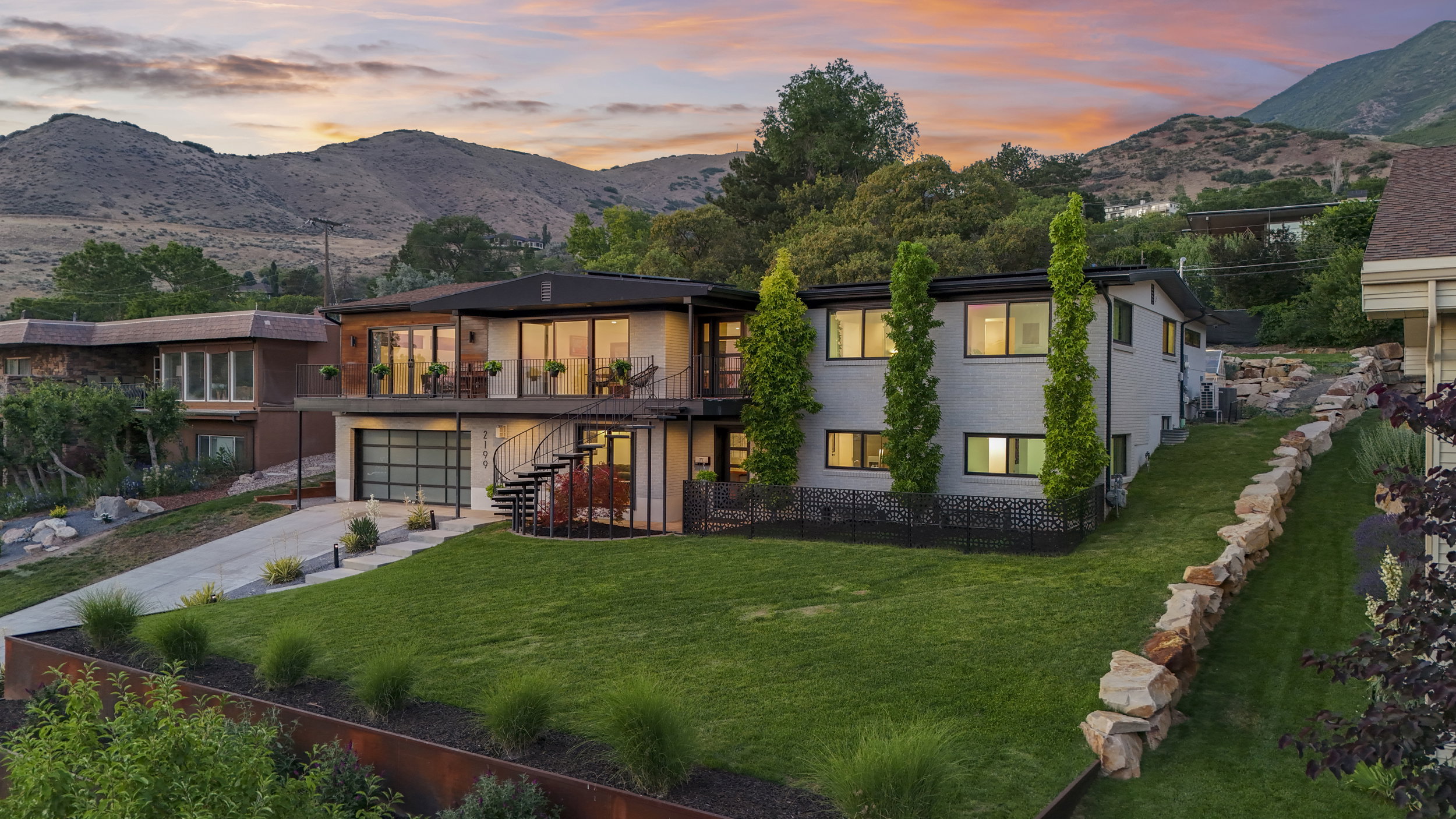 Modern architectural residence featuring multiple balconies, extensive window placements, and a spiral exterior staircase