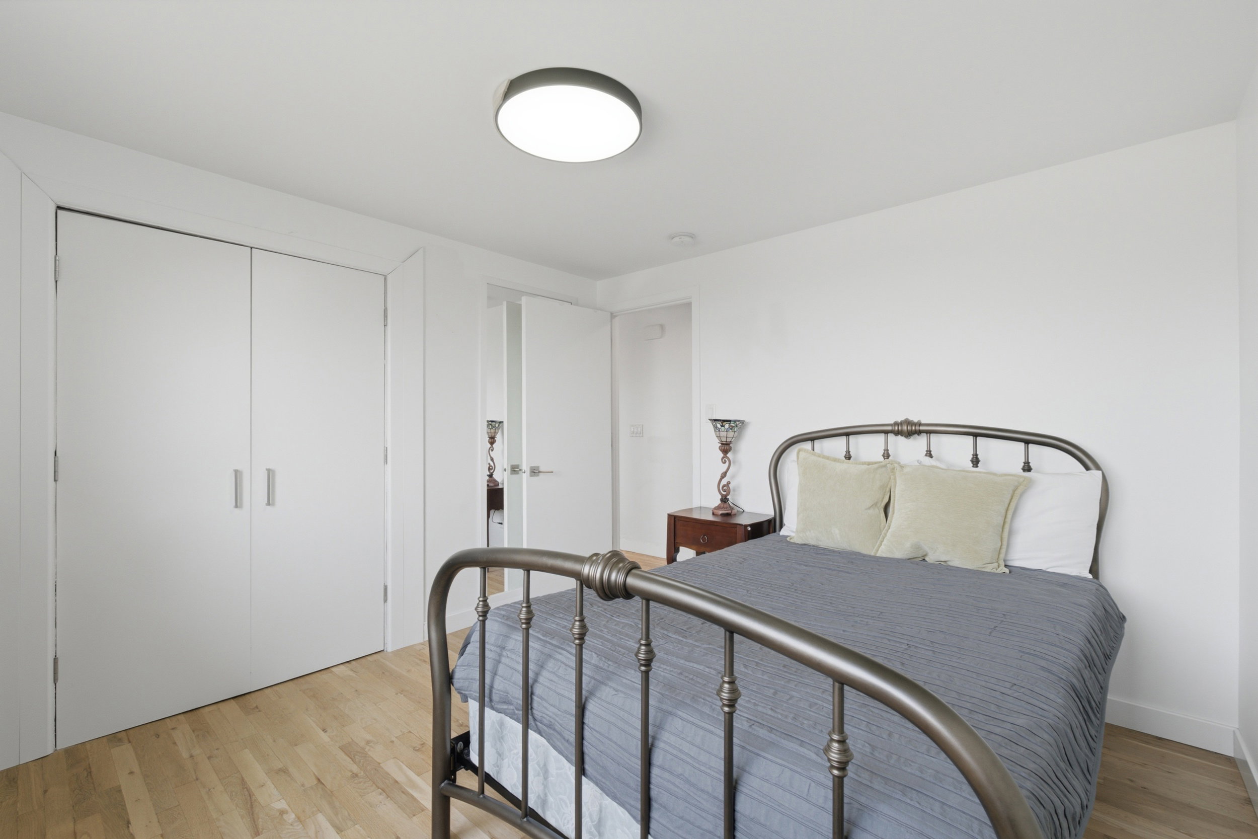 Interior room featuring light wood-finish flooring, white walls, and a contemporary flush-mount ceiling light fixture