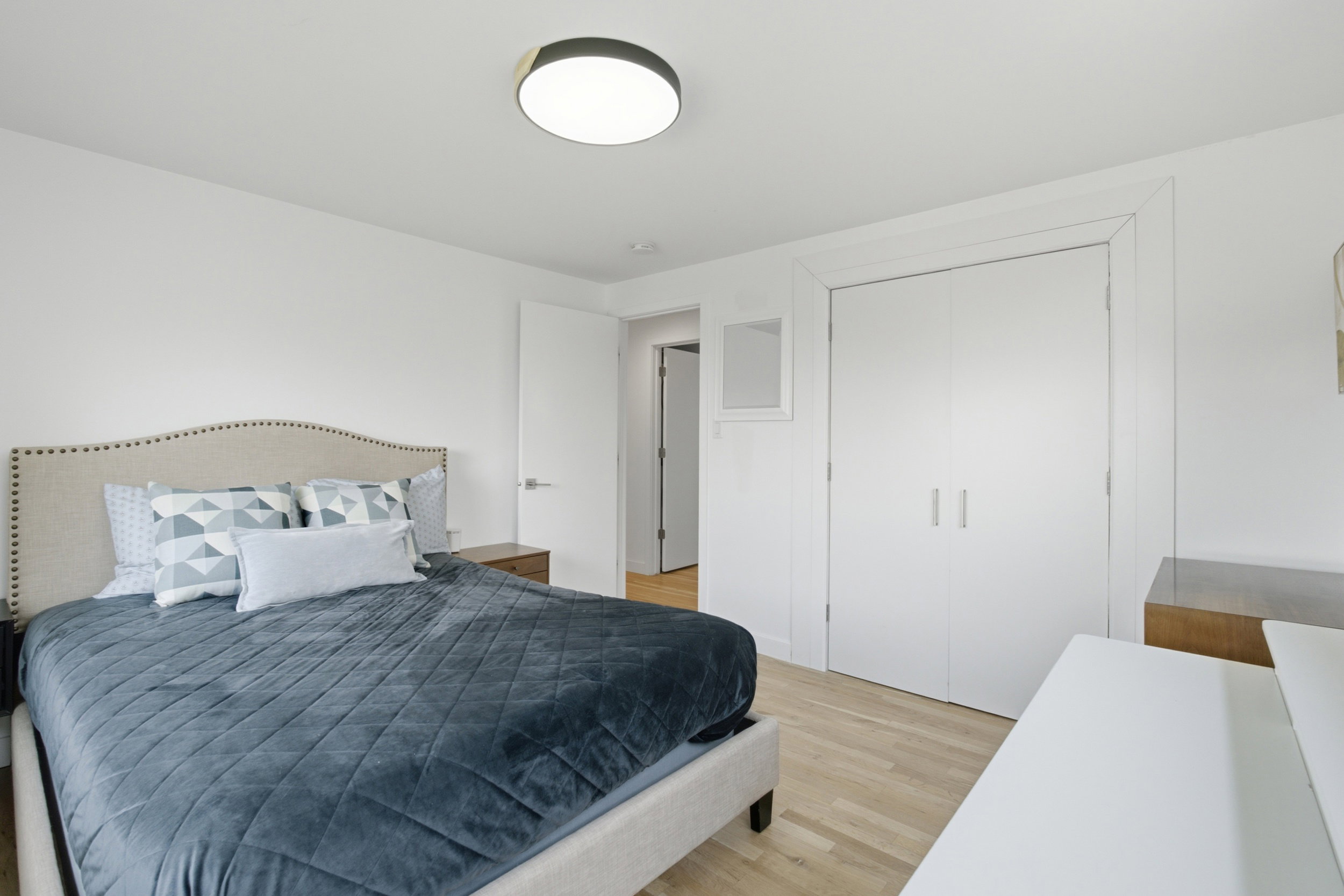Bedroom featuring light wood-finish flooring, recessed lighting, white walls, and a double-door closet