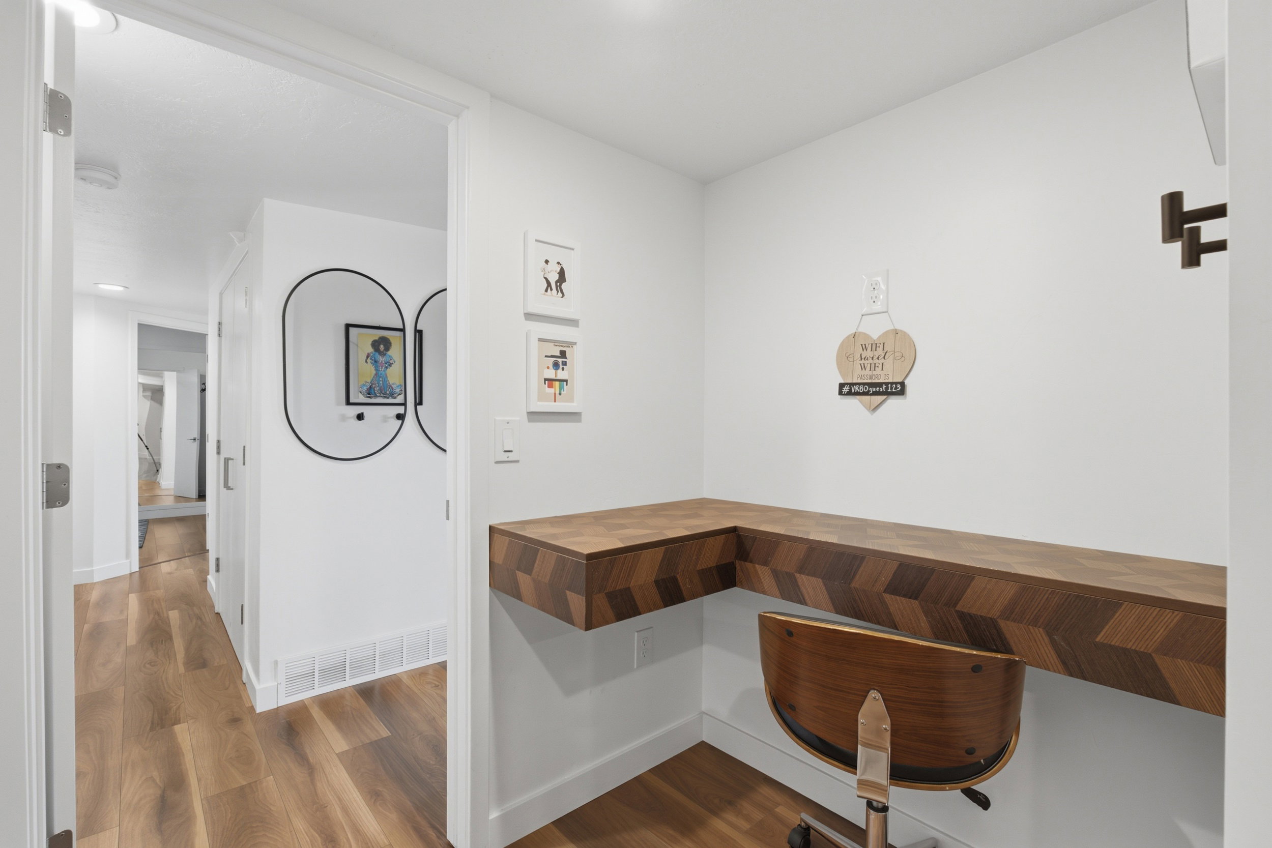 Built-in corner desk with a herringbone pattern wood-finish surface, complemented by light wood-finish flooring