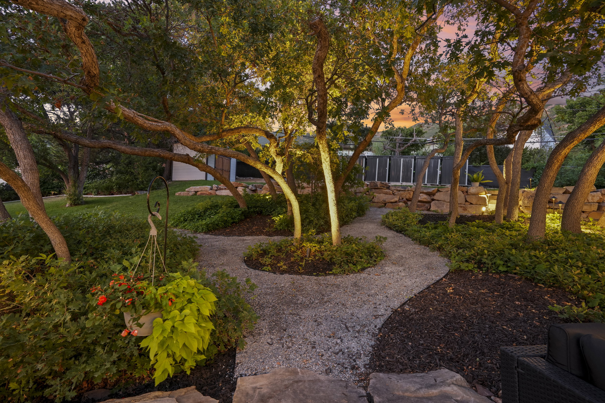 Gravel pathways winding through mature trees and planted garden beds