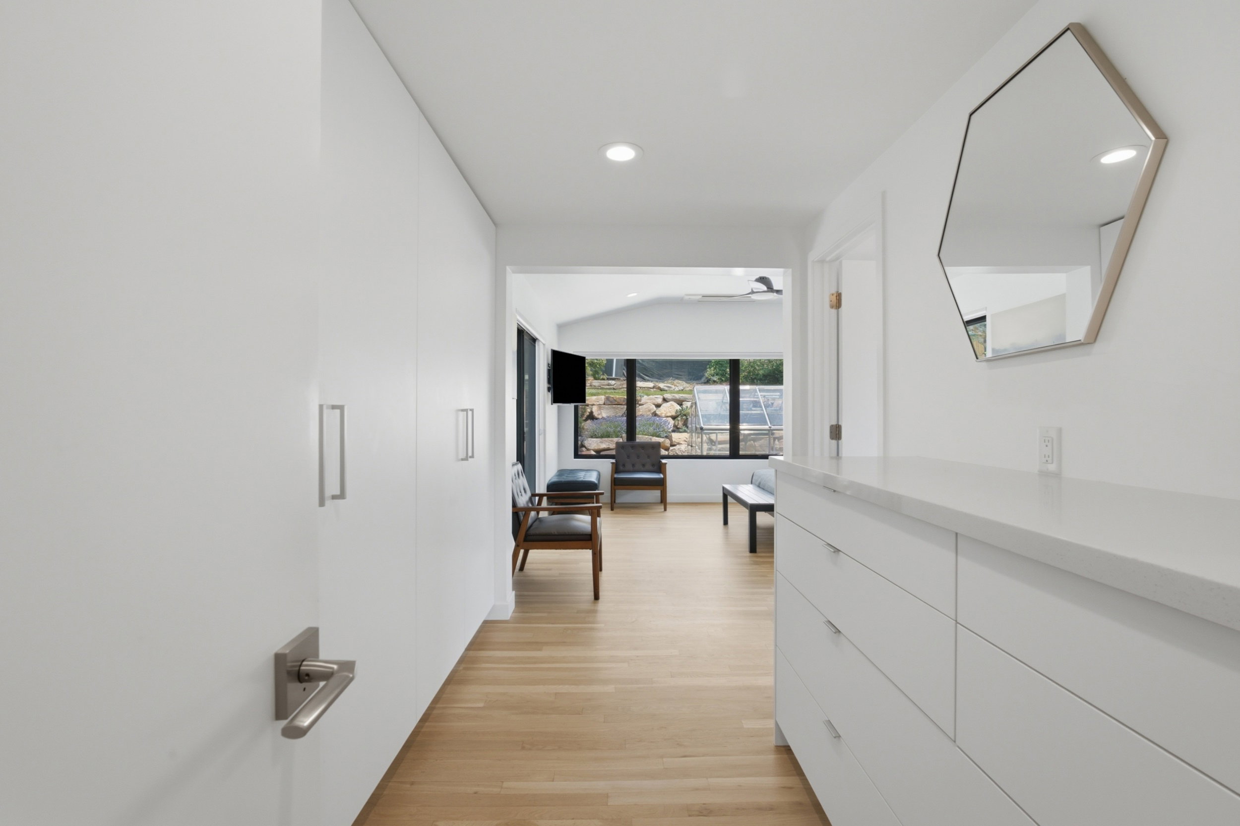 Hallway featuring light wood-finish flooring, recessed lighting, and a built-in white cabinetry unit with a light-colored countertop