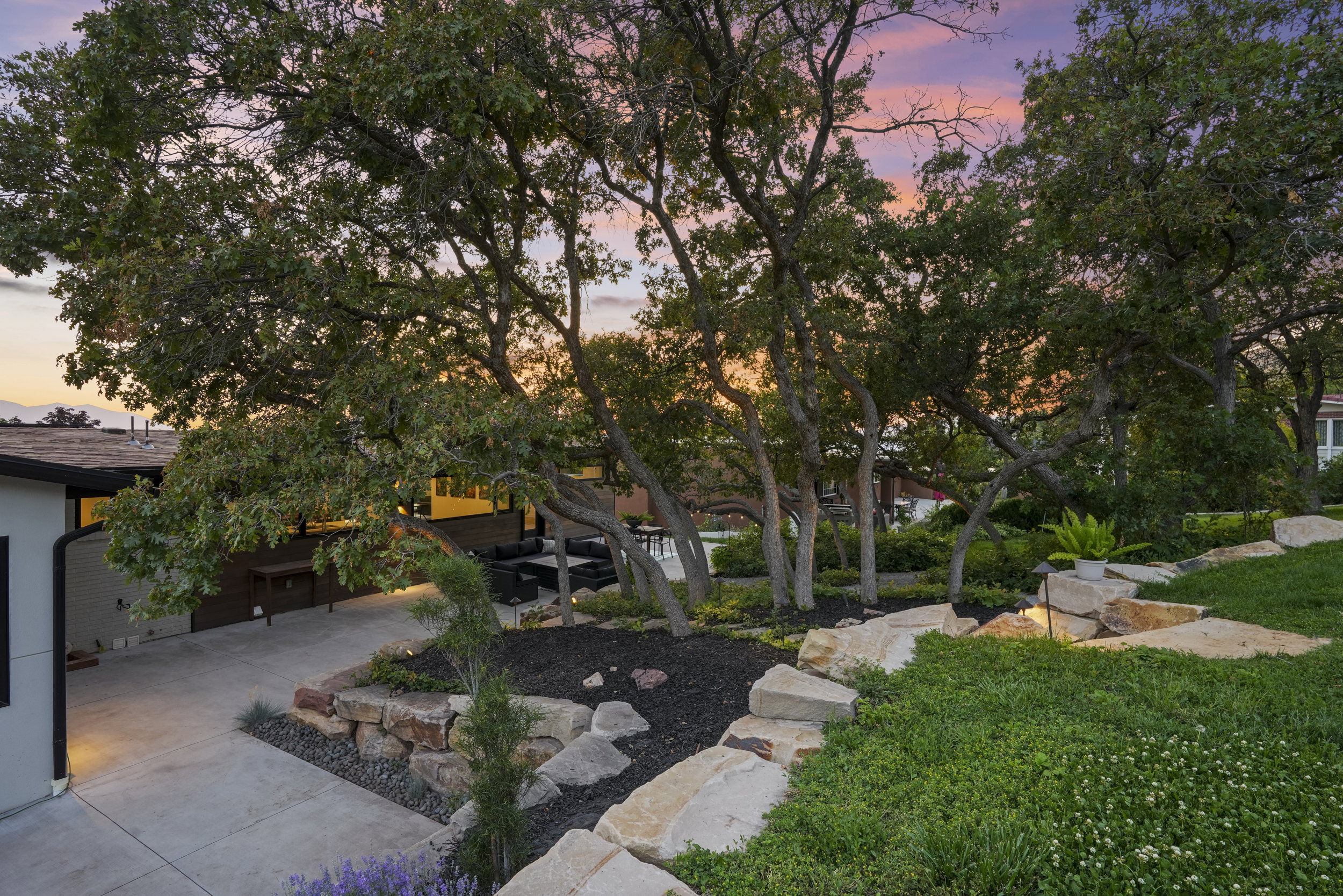 Manicured landscaping featuring mature trees and a tiered rock garden