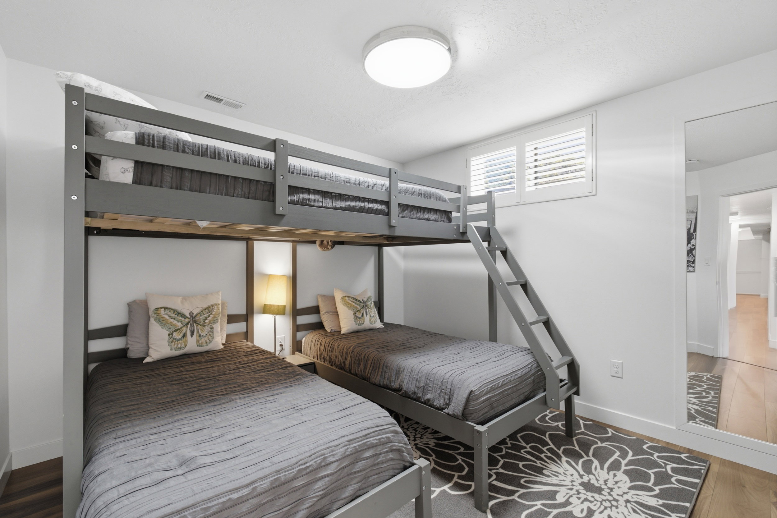 Room featuring a large full-length mirror and a window with white louvered shutters