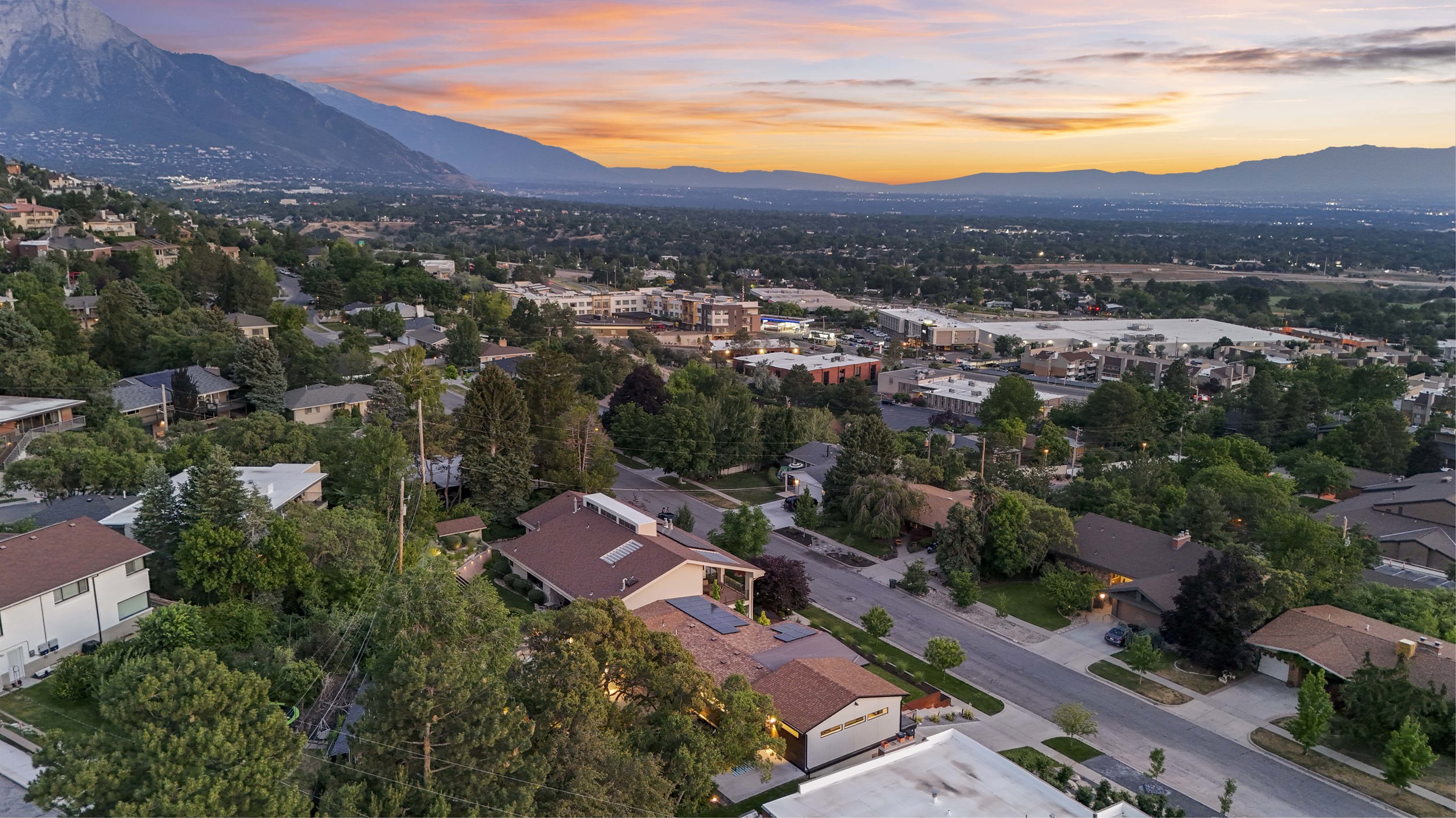Expansive neighborhood featuring mature trees and established residences, set against a backdrop of distant mountains and a broad valley